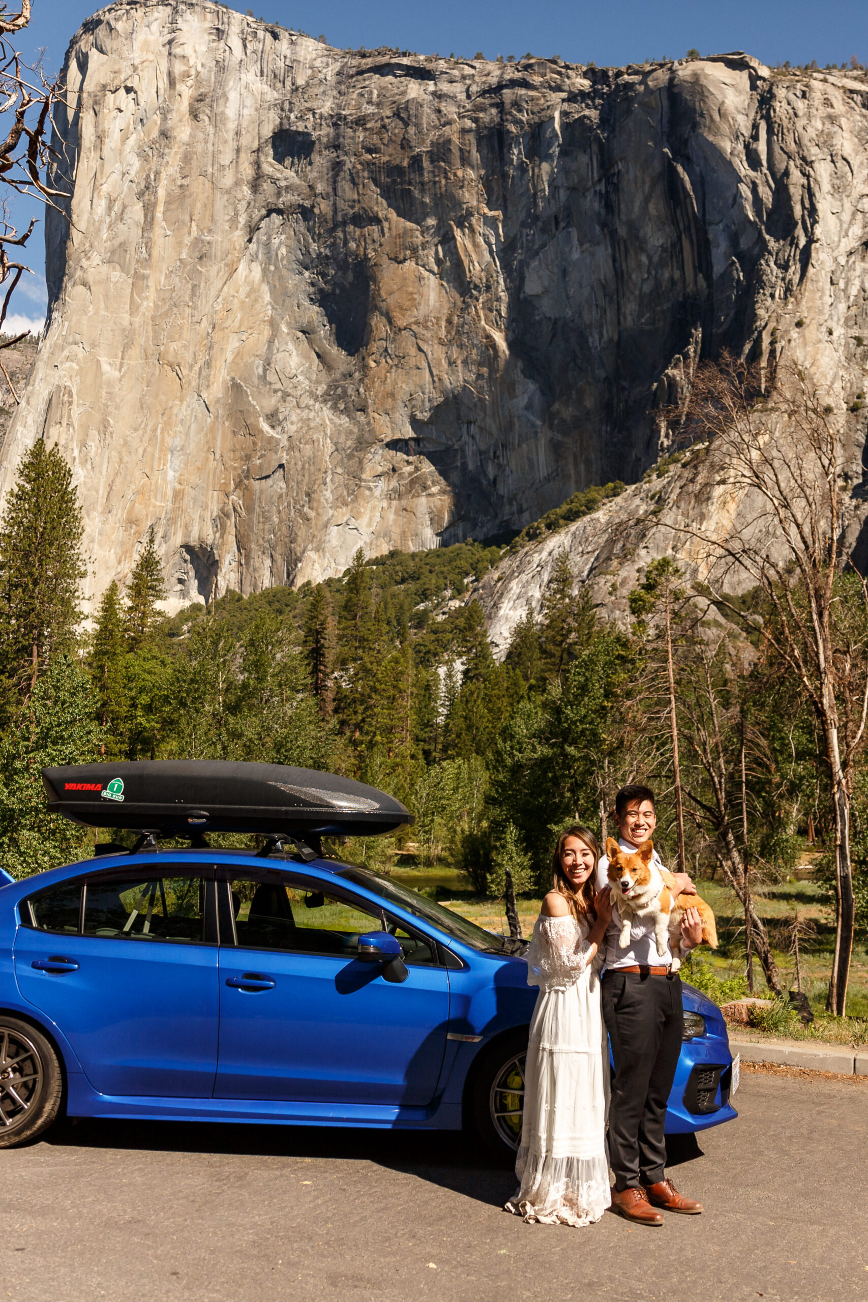 a married couple holding their dog next to a huge rock during their After Wedding Photoshoot