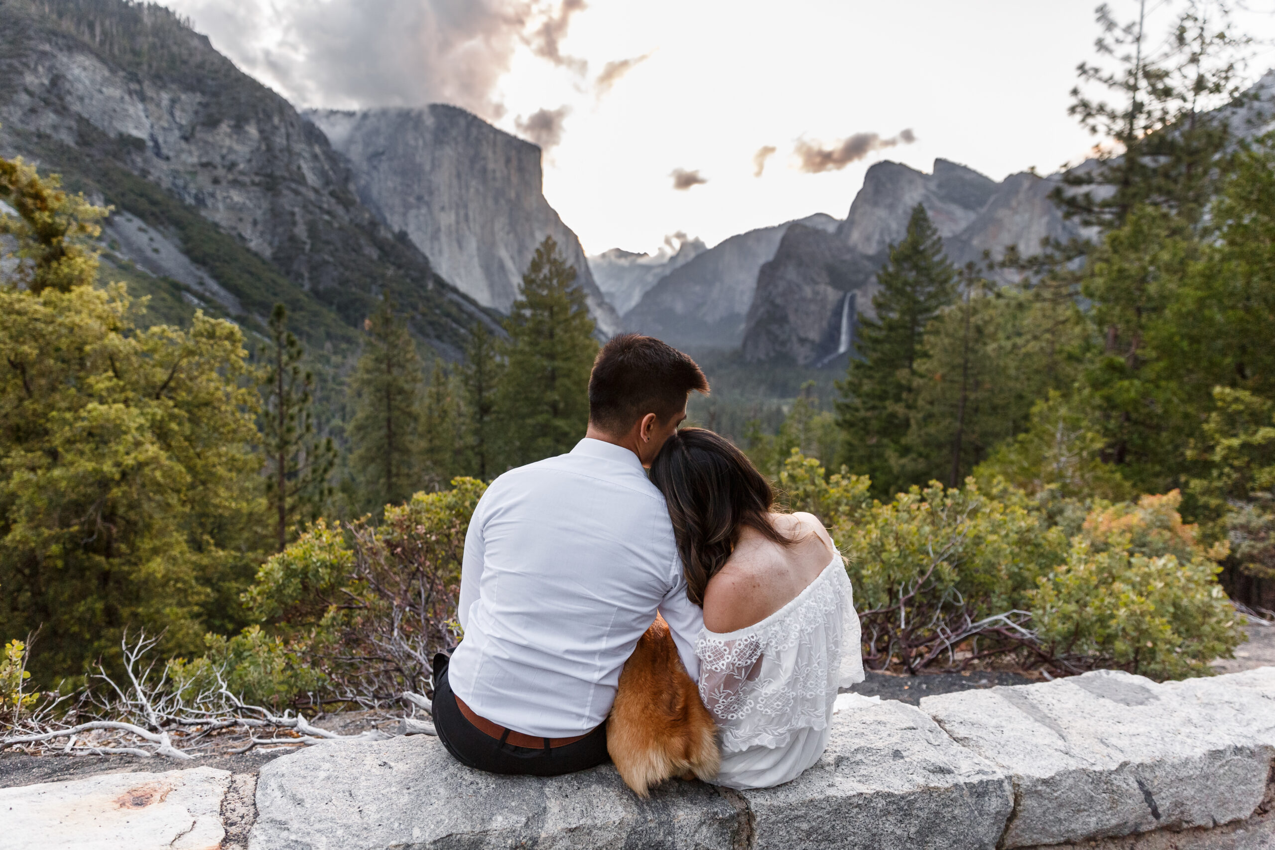 married couple with their dog sitting on a ledge taking in the view during their After Wedding Photoshoot