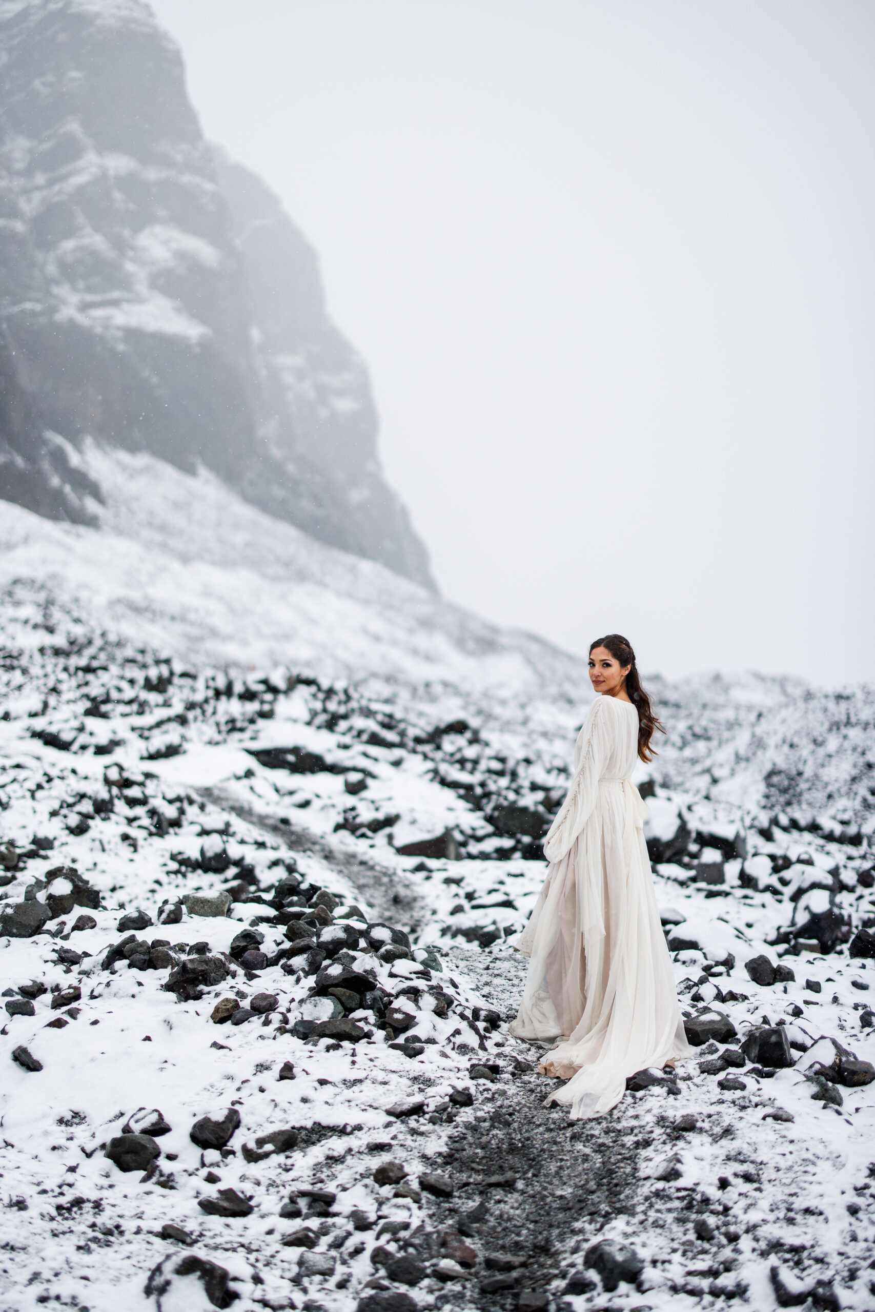 a bride wearing a long sleeve wedding dress and keeping warm during a winter elopement