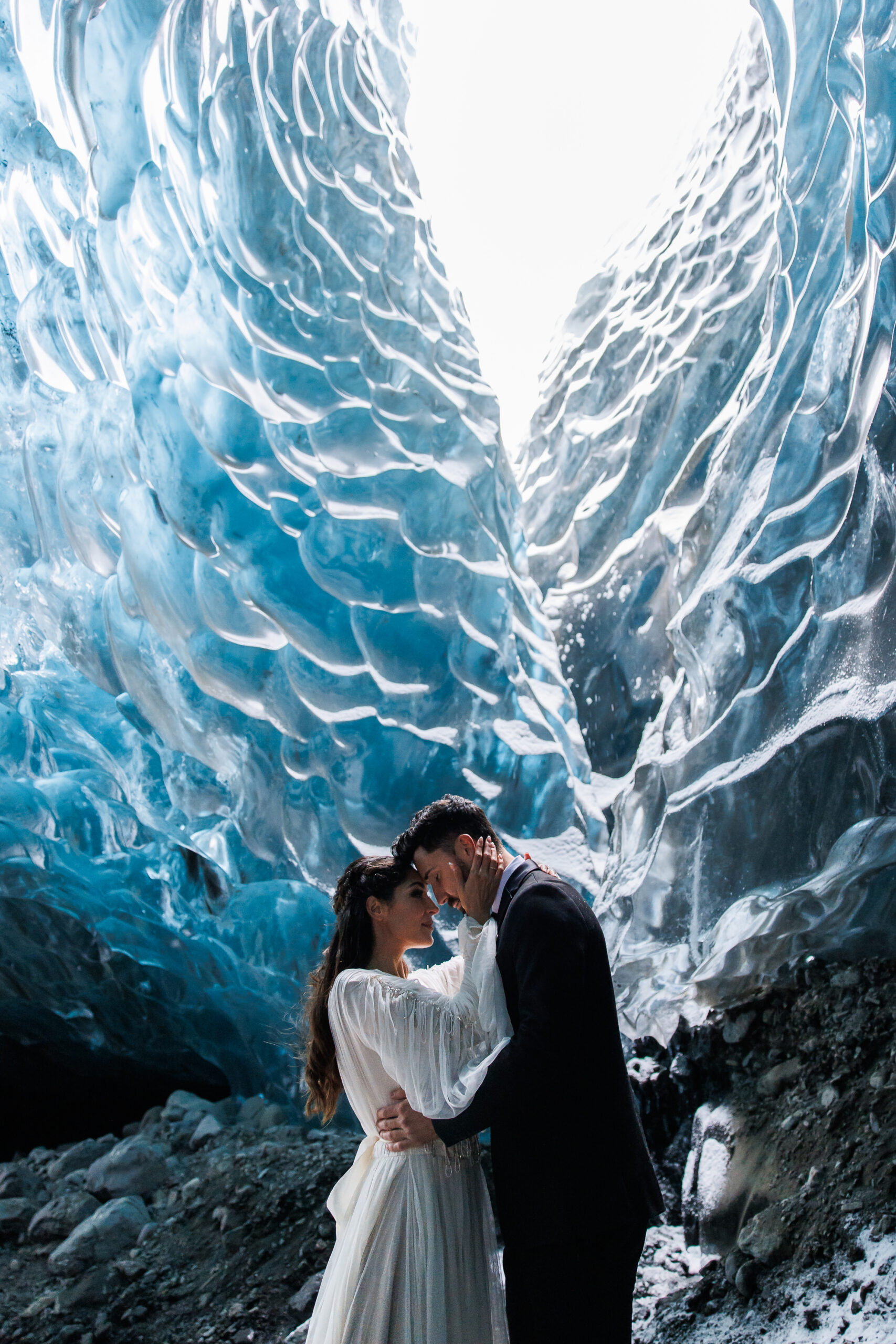 bridal couple portrait in the ice caves with an opening to to sky above them 