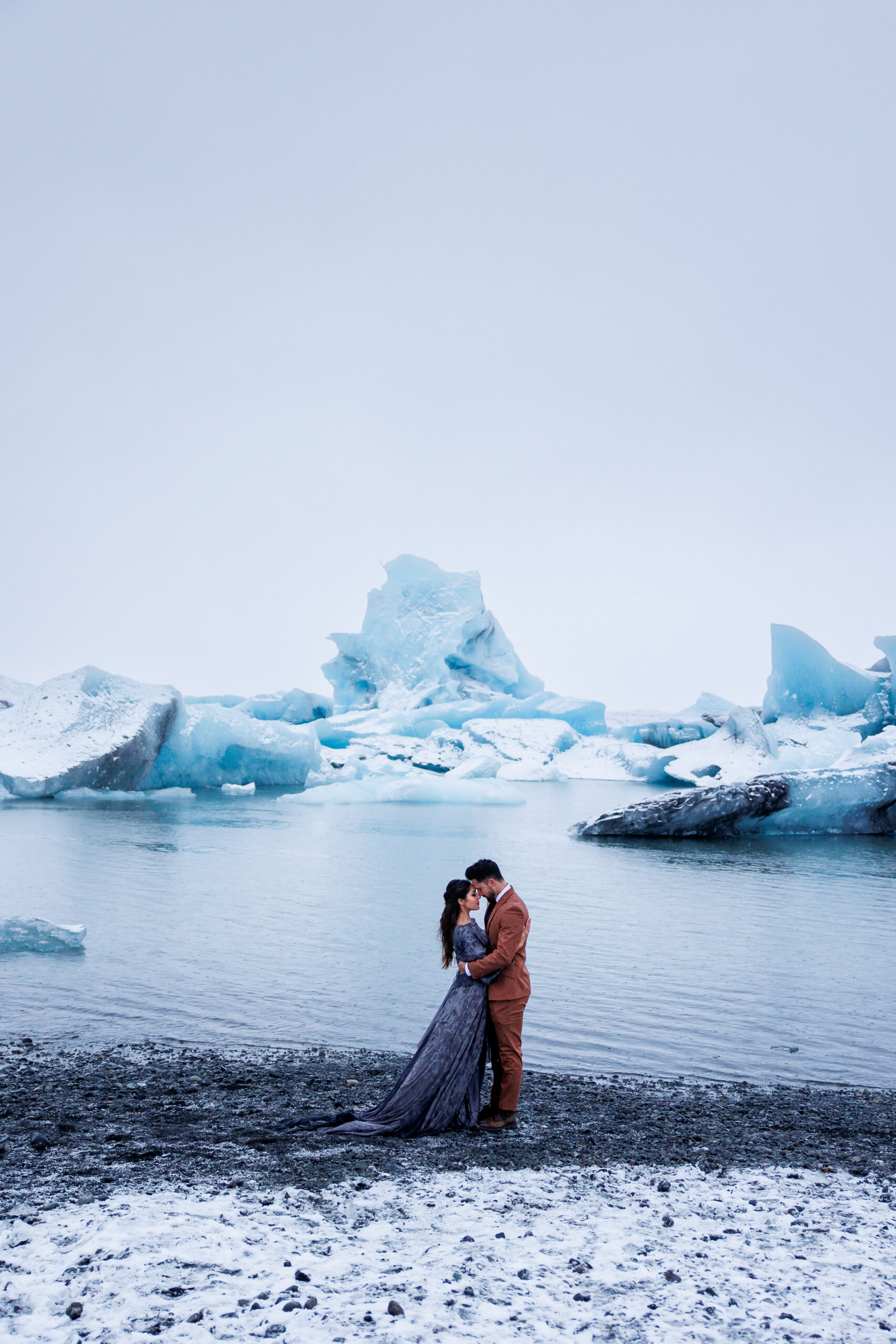 wedding couple holding each other with icebergs in the background 