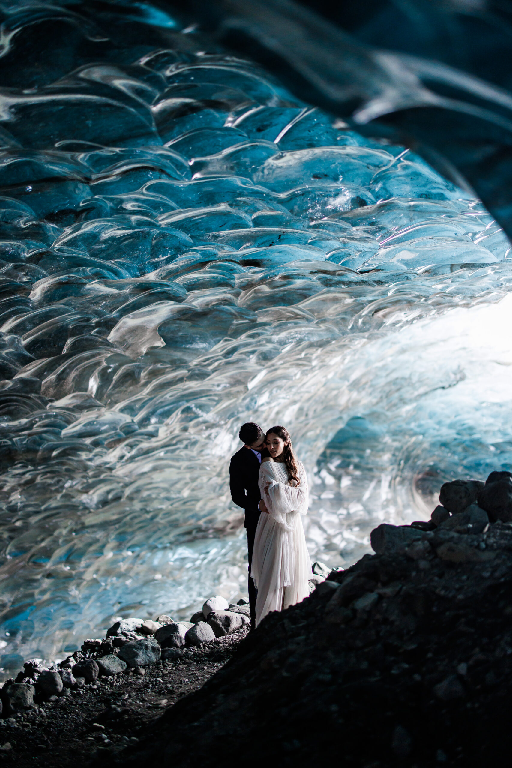 bride and groom standing in the ice caves together 