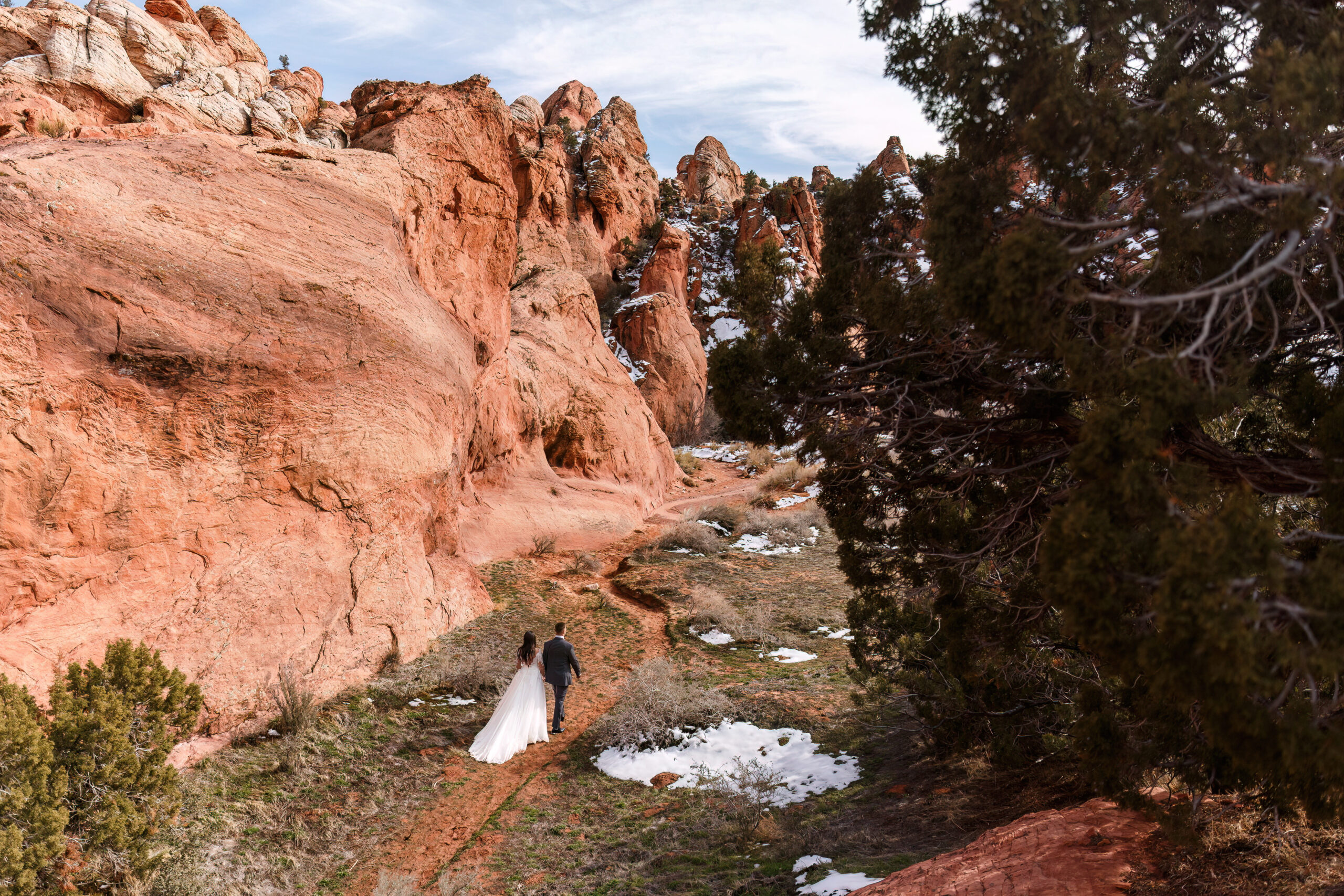 bride and groom walking alongside some red rocks at horseshoe bend 