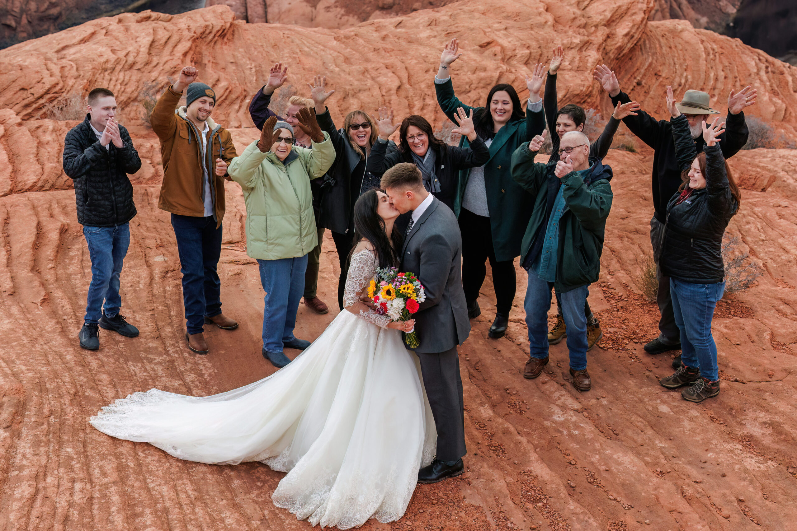 winter elopement guests cheering on the bride and groom as they kiss