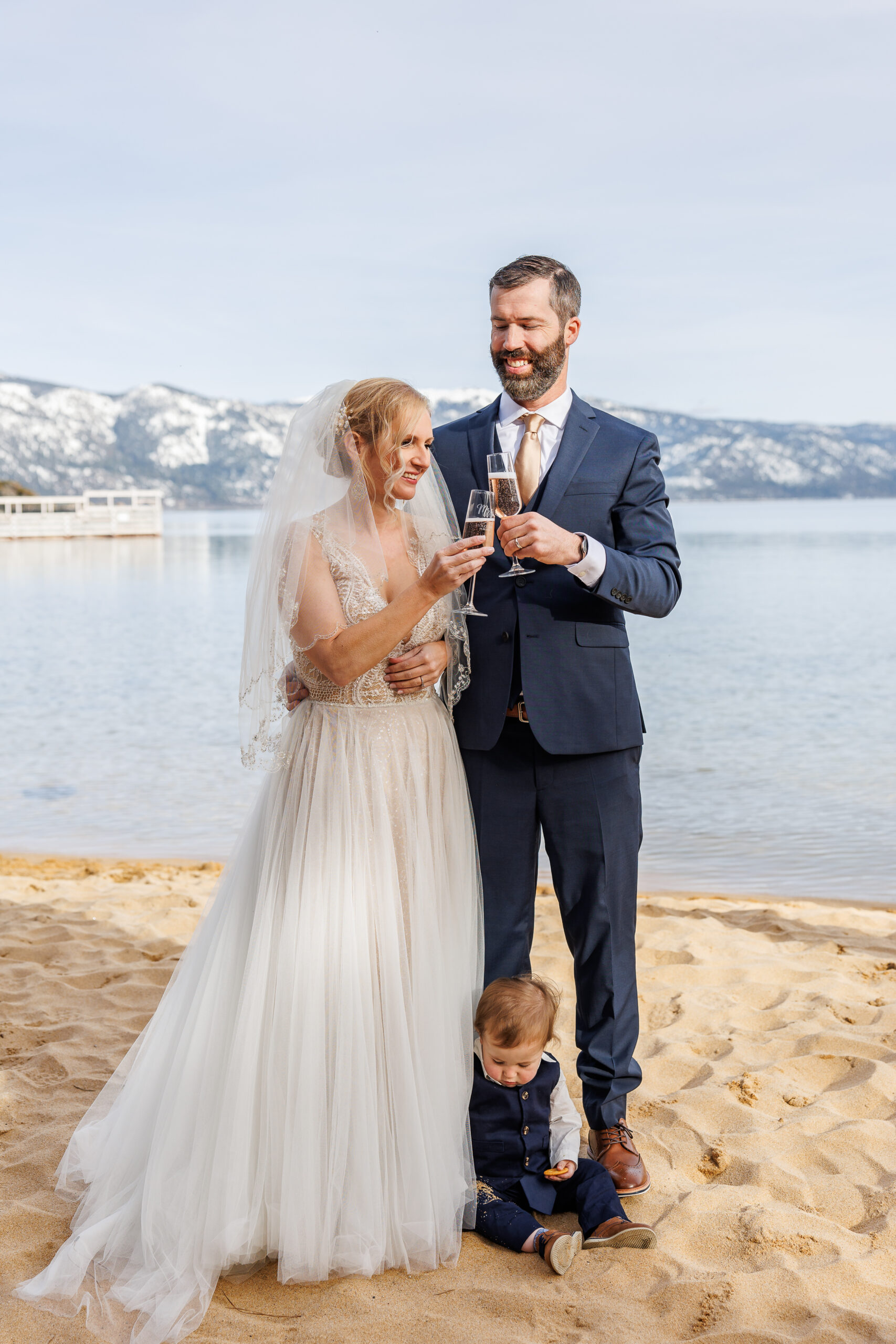 bride and groom toasting as their baby sits by their feet during their winter elopement