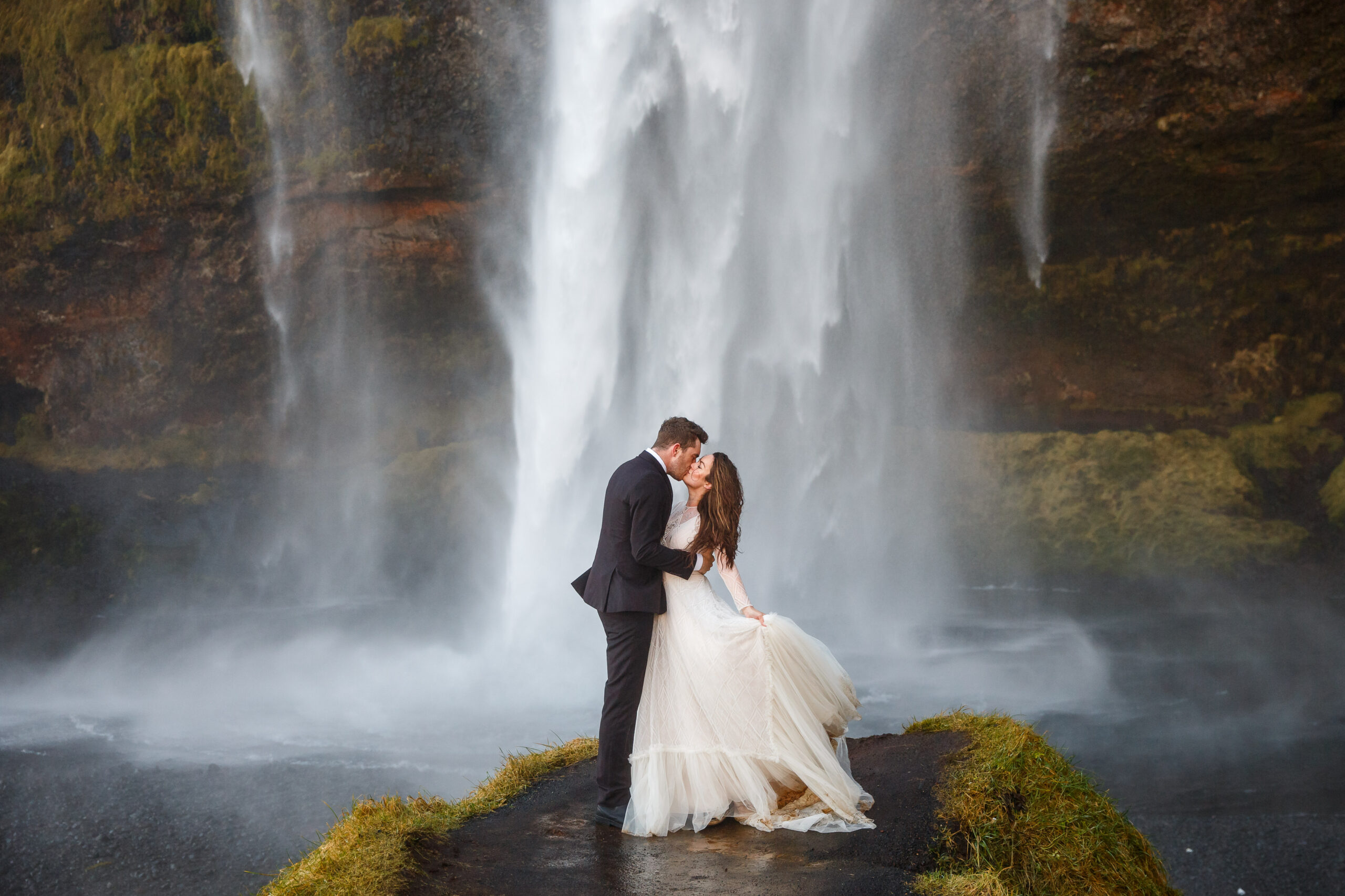 a married couple under a waterfall in Iceland for their winter elopement