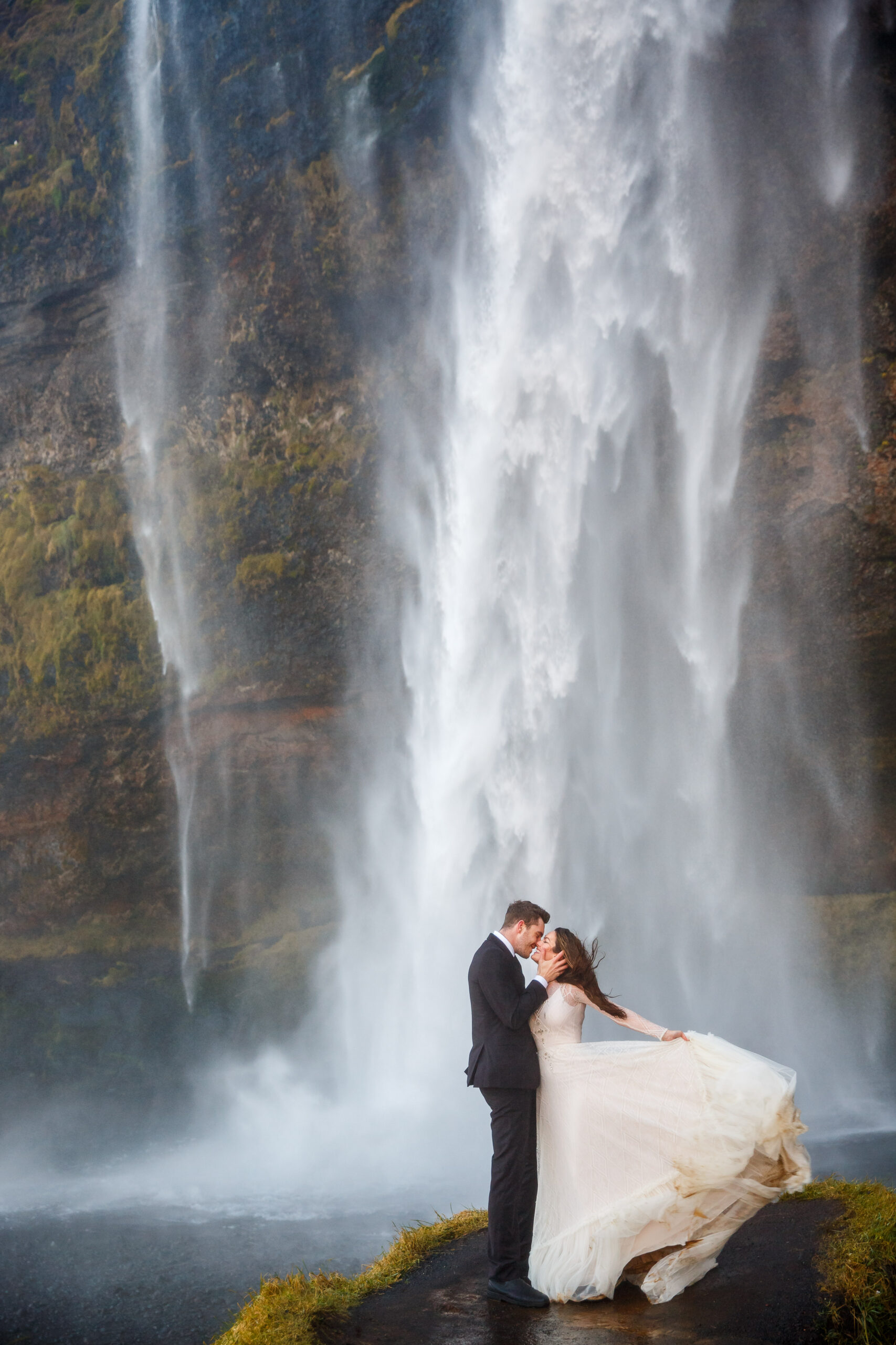 bride and groom kissing under the powerful waterfall in Iceland 