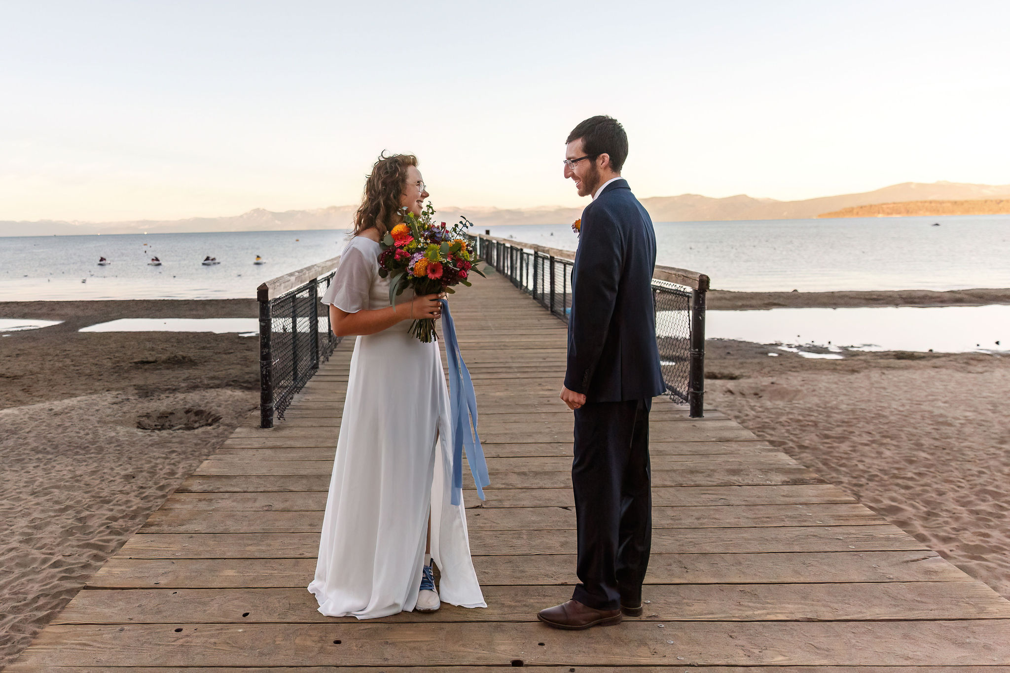 bride and groom standing on a doc after their sunrise first look 