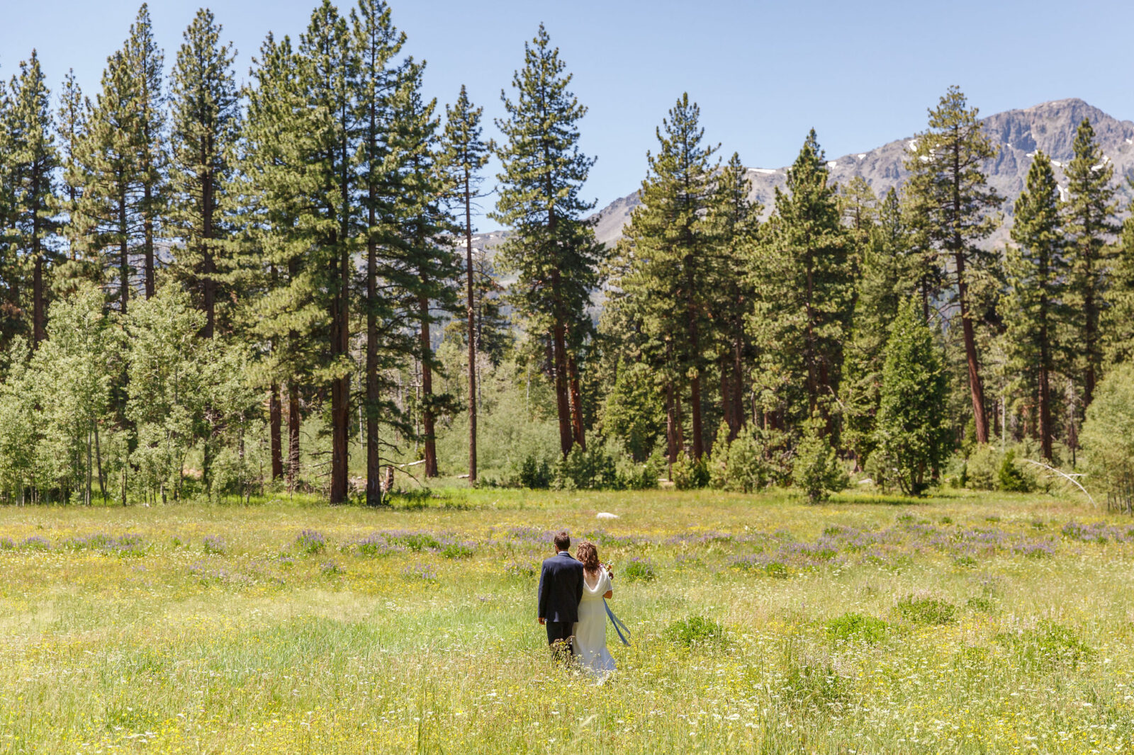 bride and groom walking trough wildflower meadows as an after Elopement Activity 