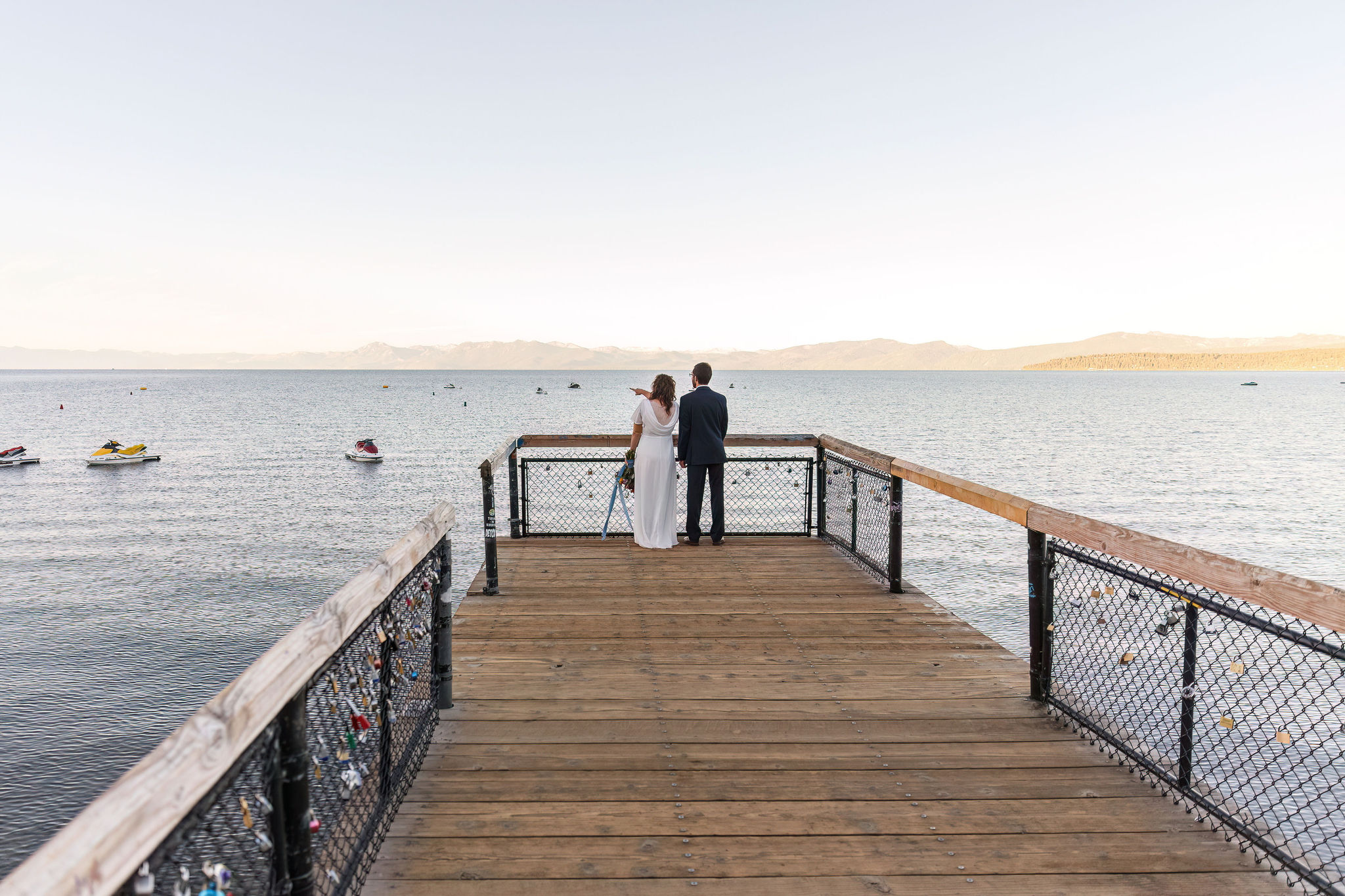 bride and groom standing at the end of a dock looking out at Lake Tahoe 