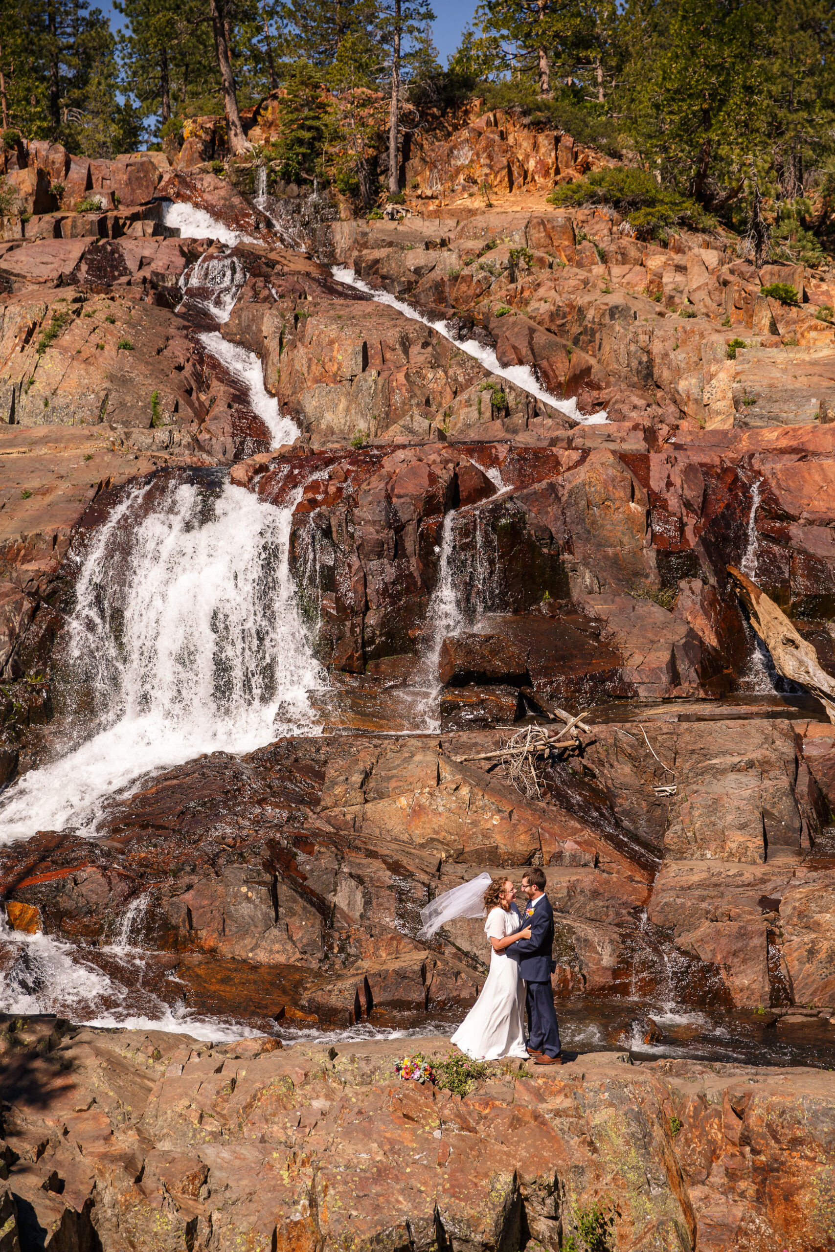 bride and groom standing in front of a waterfall for an adventurous Elopement Activity