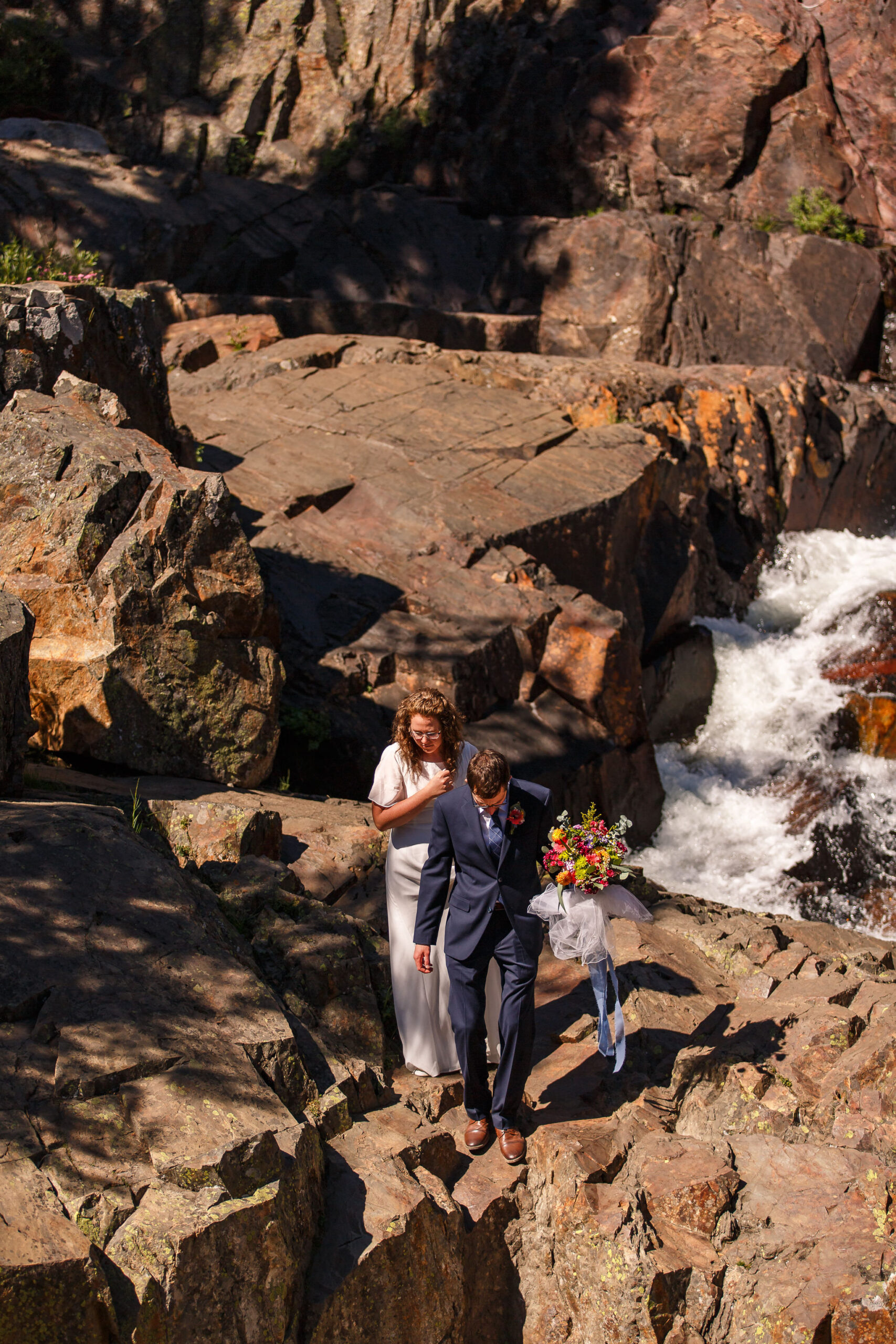 bridal couple walking through the rocks together 