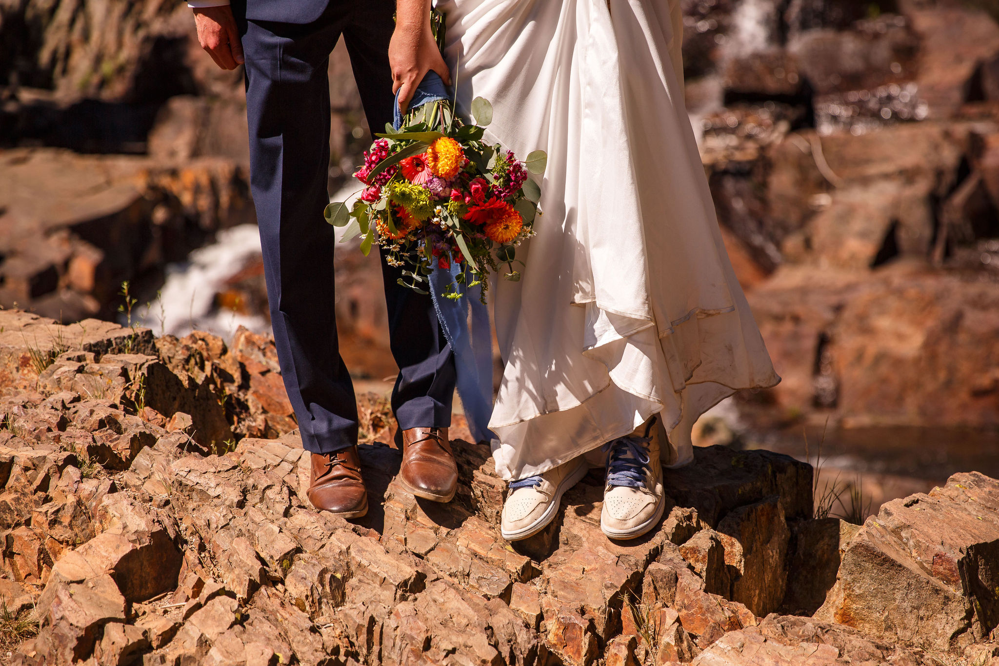 the bride and groom's lower halves as they satnd on rocks during their Elopement Activity 