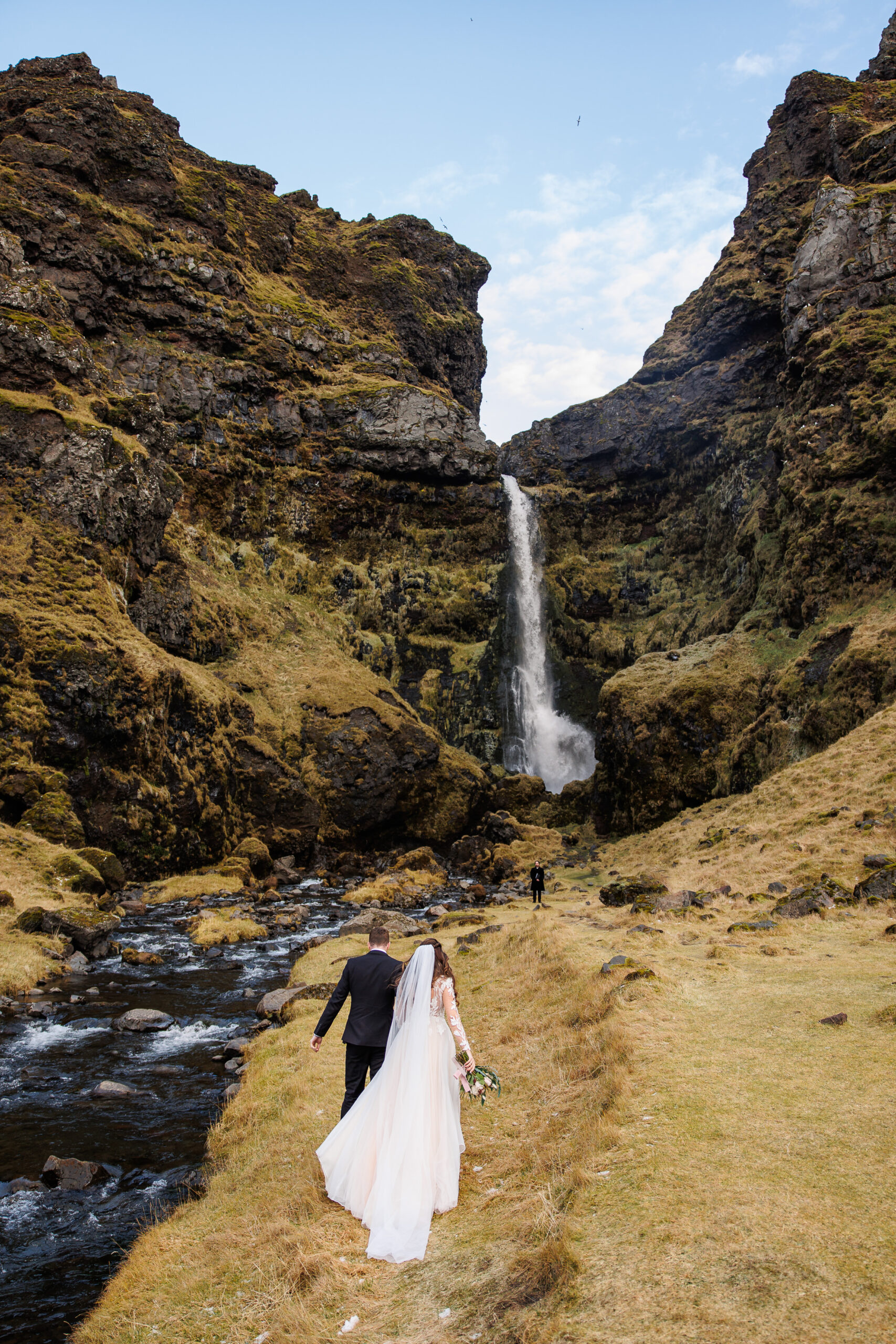 bridal couple walking up the a waterfall for their winter elopement