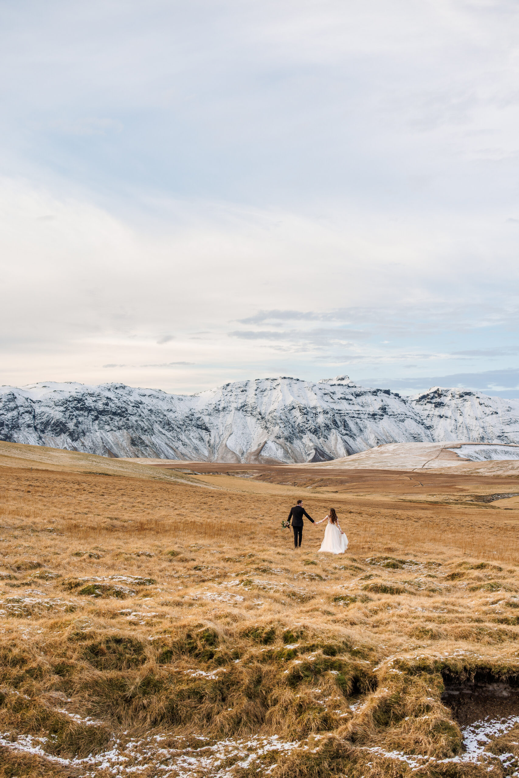 bride and groom walking through a barren and snowy field in Iceland 