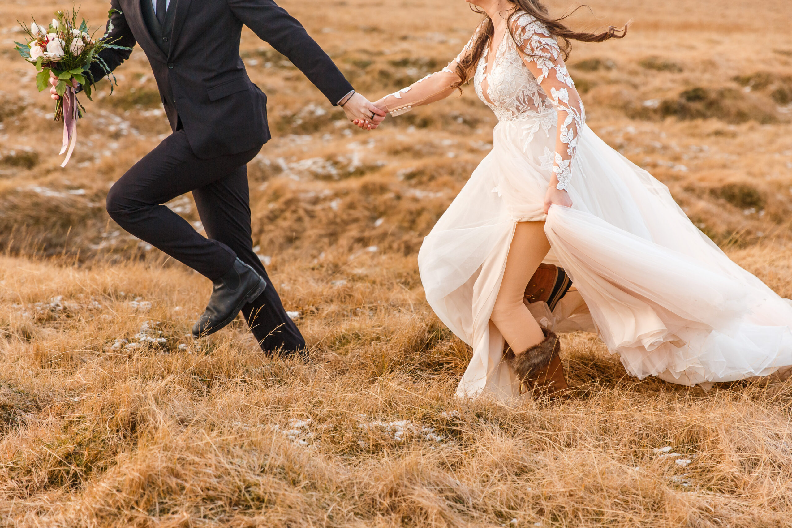 a married couple running hand in hand together, the bride showing her leggings underneath her dress to keep warm for her winter elopement