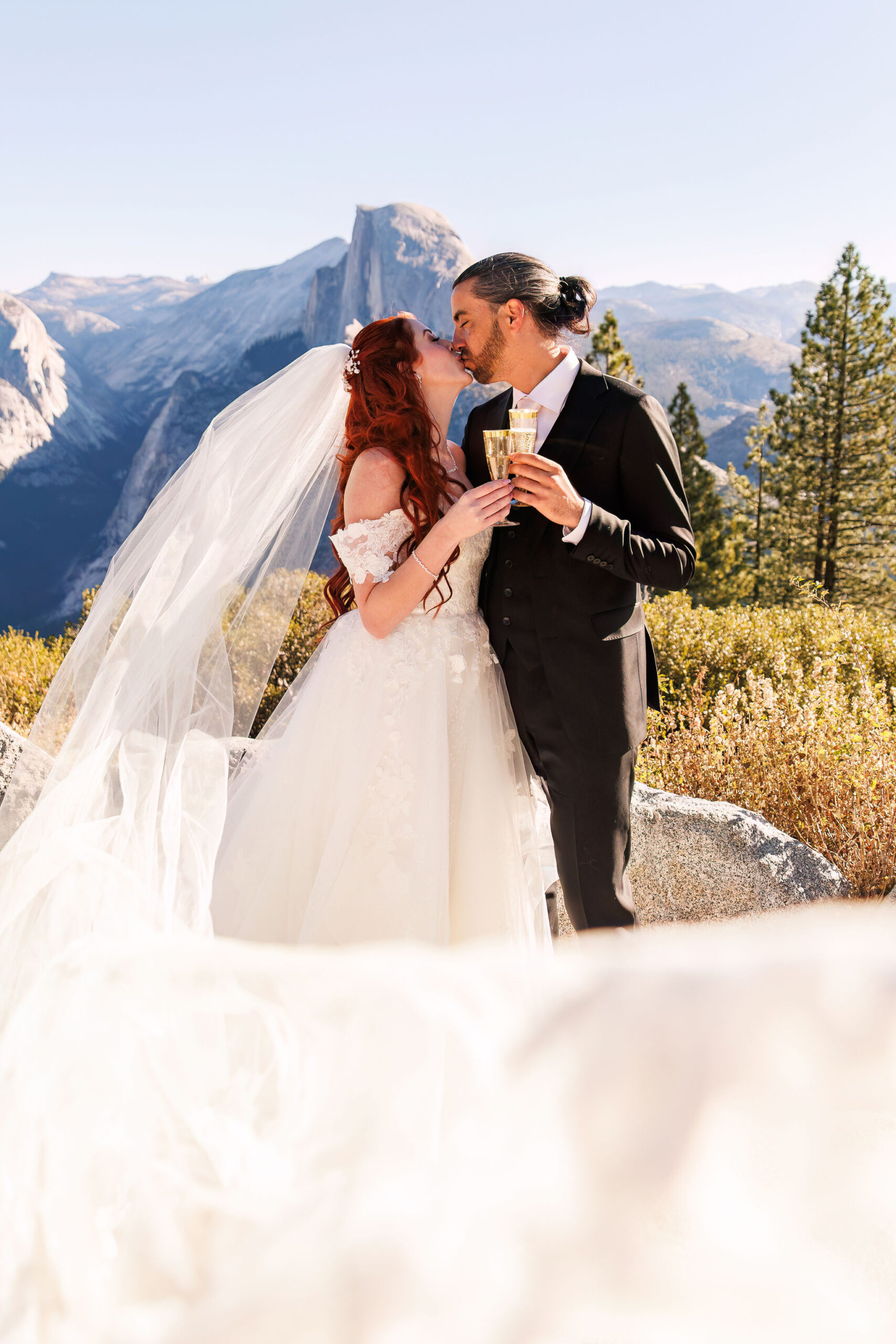 bride and groom kissing while holding their champagne 