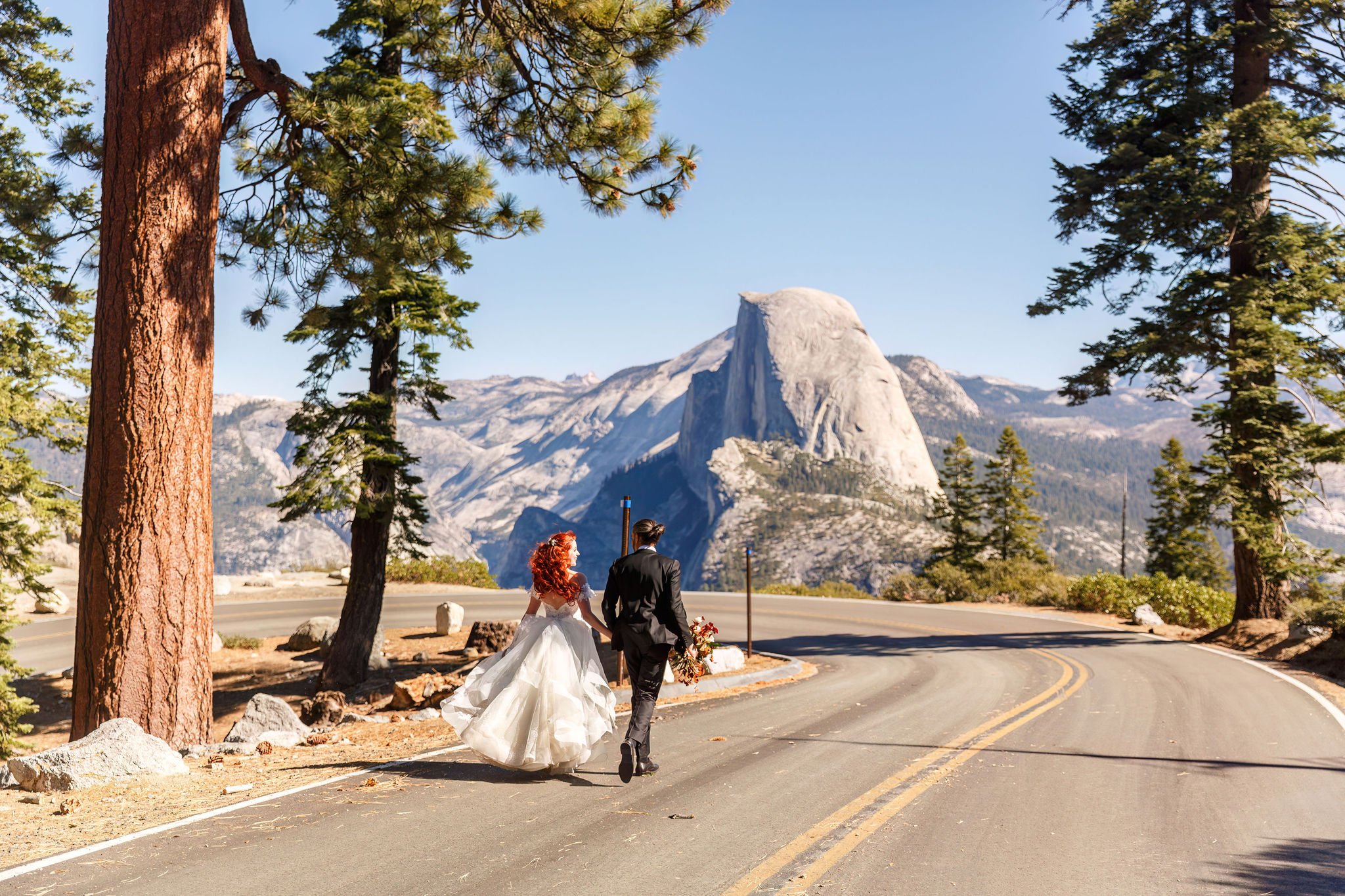 bride and groom running together on a road for Yosemite elopement photos 