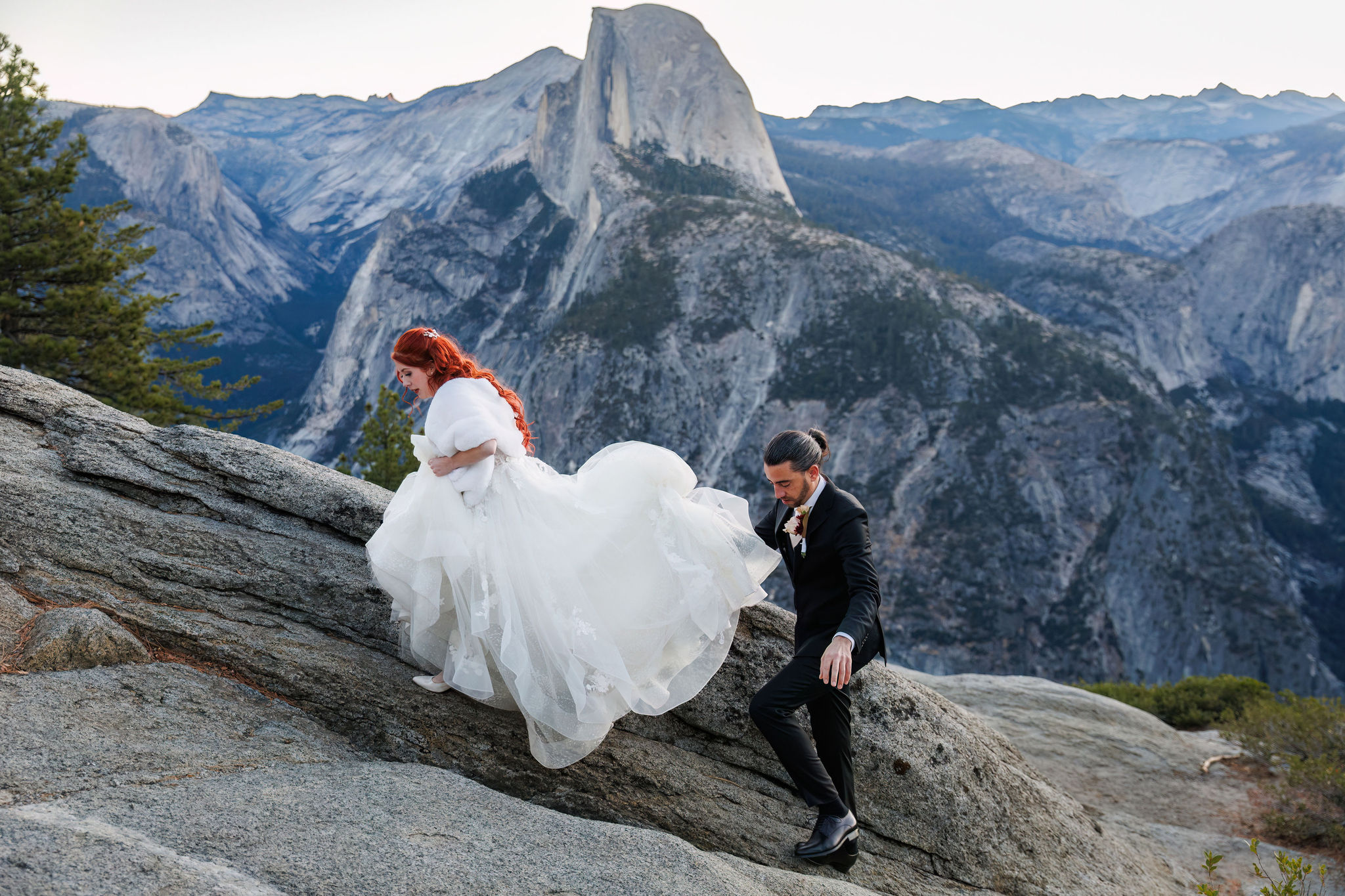 groom helping bride walk up the rocks 