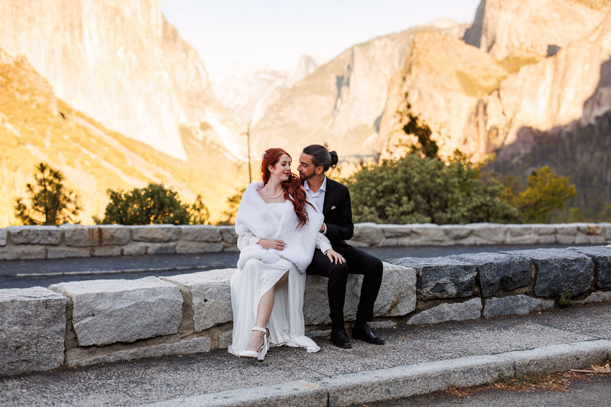 newly weds sitting on a ledge together 