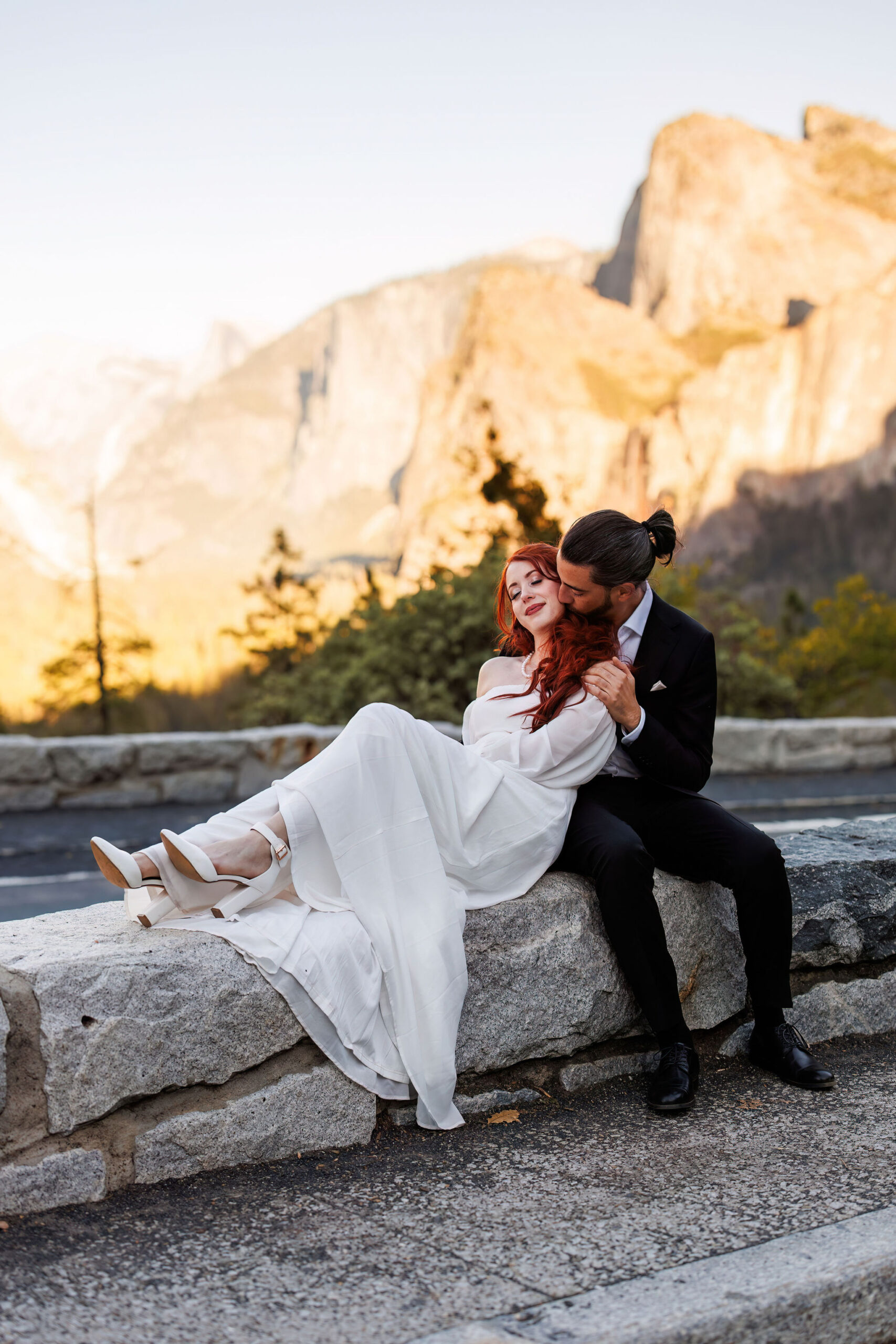 bride and groom sitting on a ledge in Yosemite together 