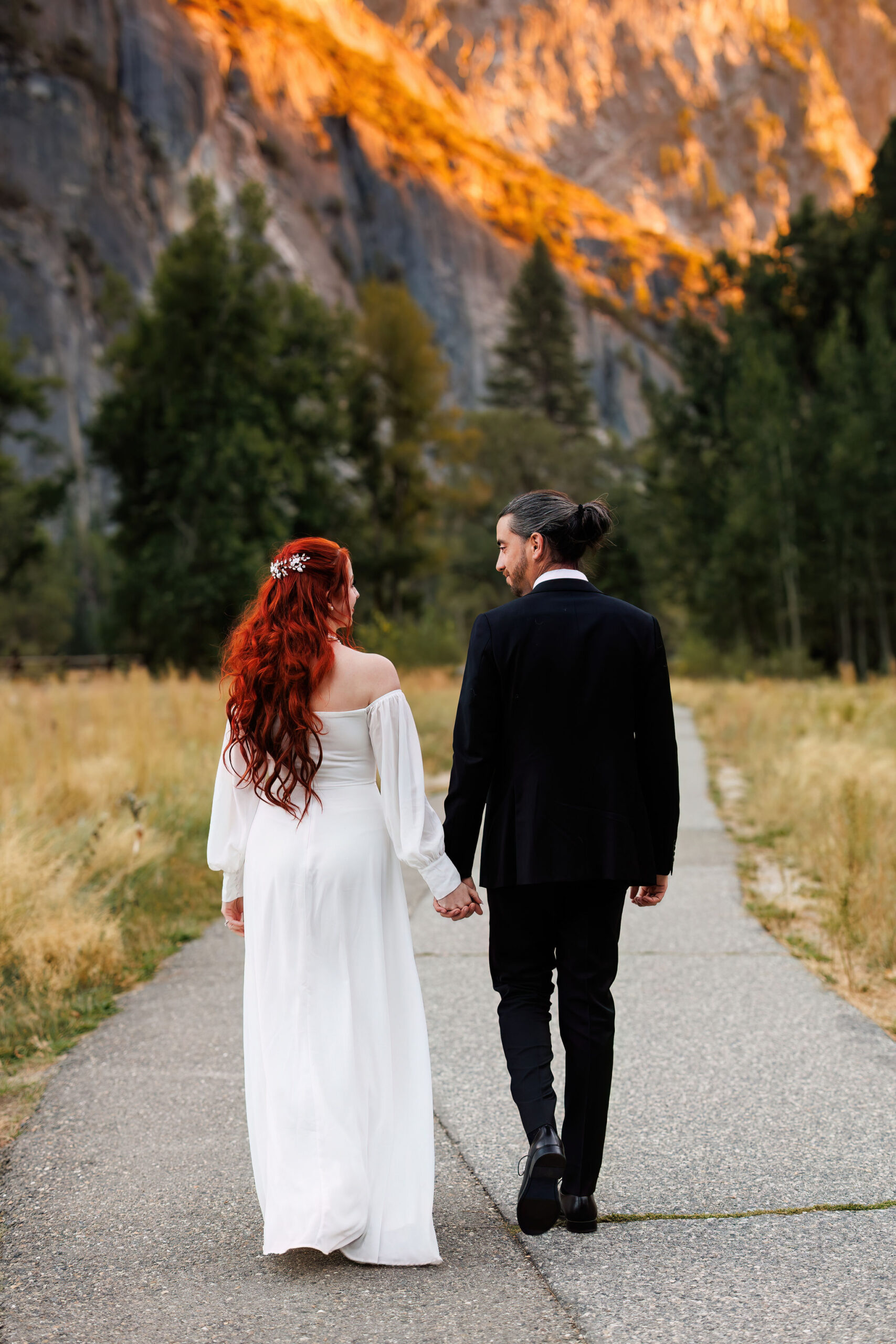 bride and groom walking hand in hand through Yosemite