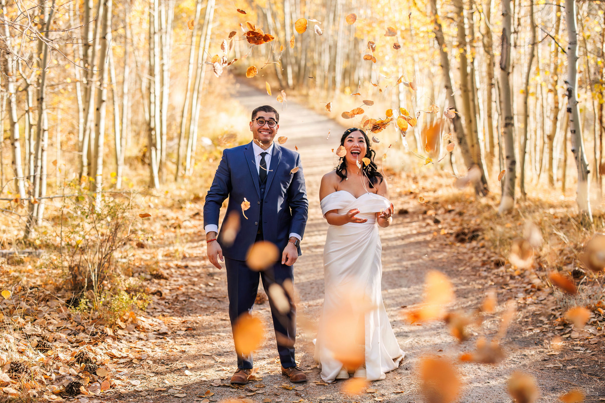 bride and groom having fun, throwing leaves at their elopement 