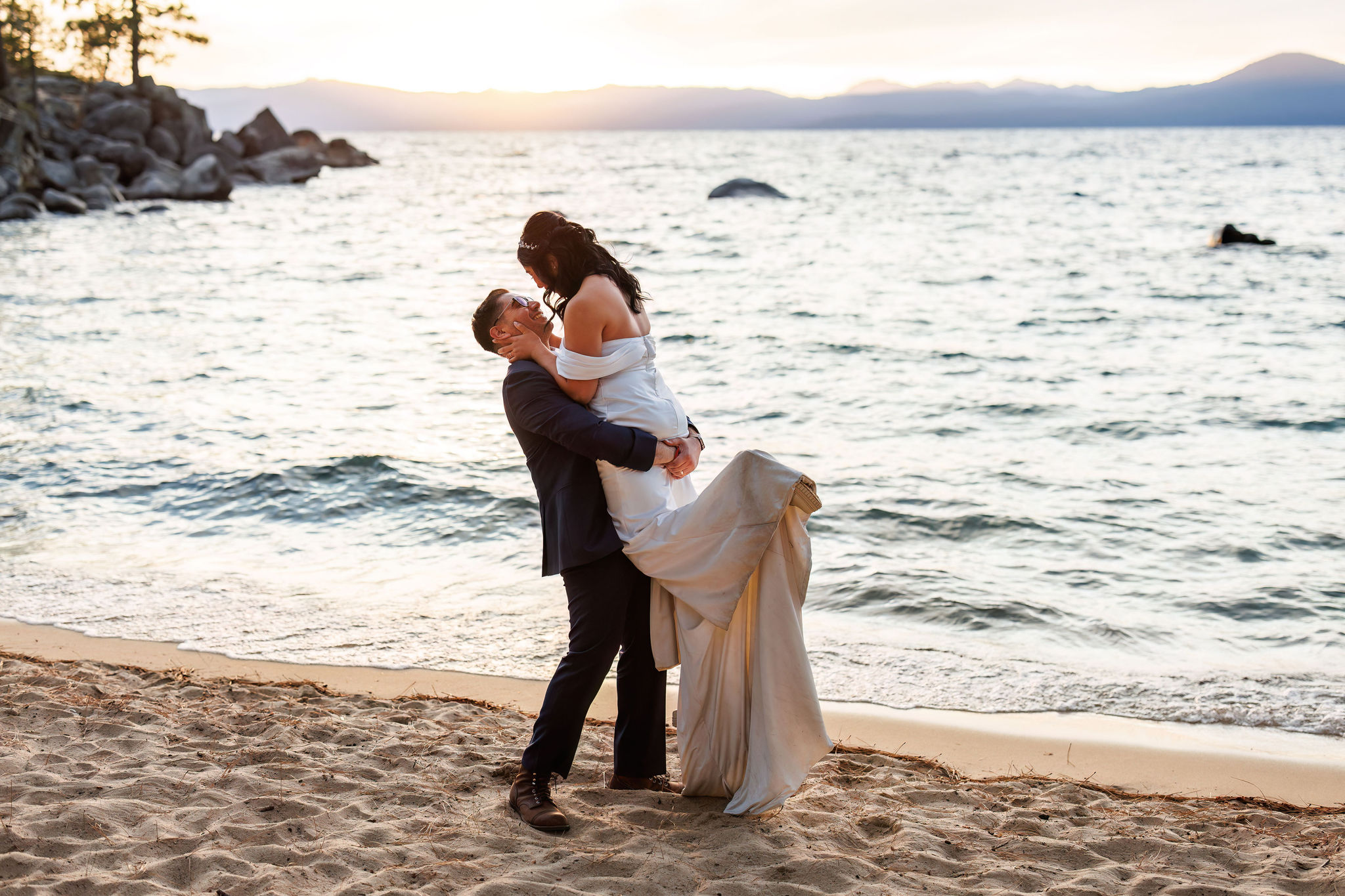 groom holding up the bride on the beach in Lake Tahoe 