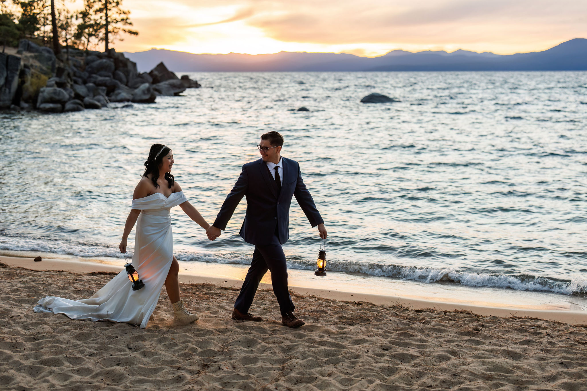 bride and groom walking down the beach with lanterns 