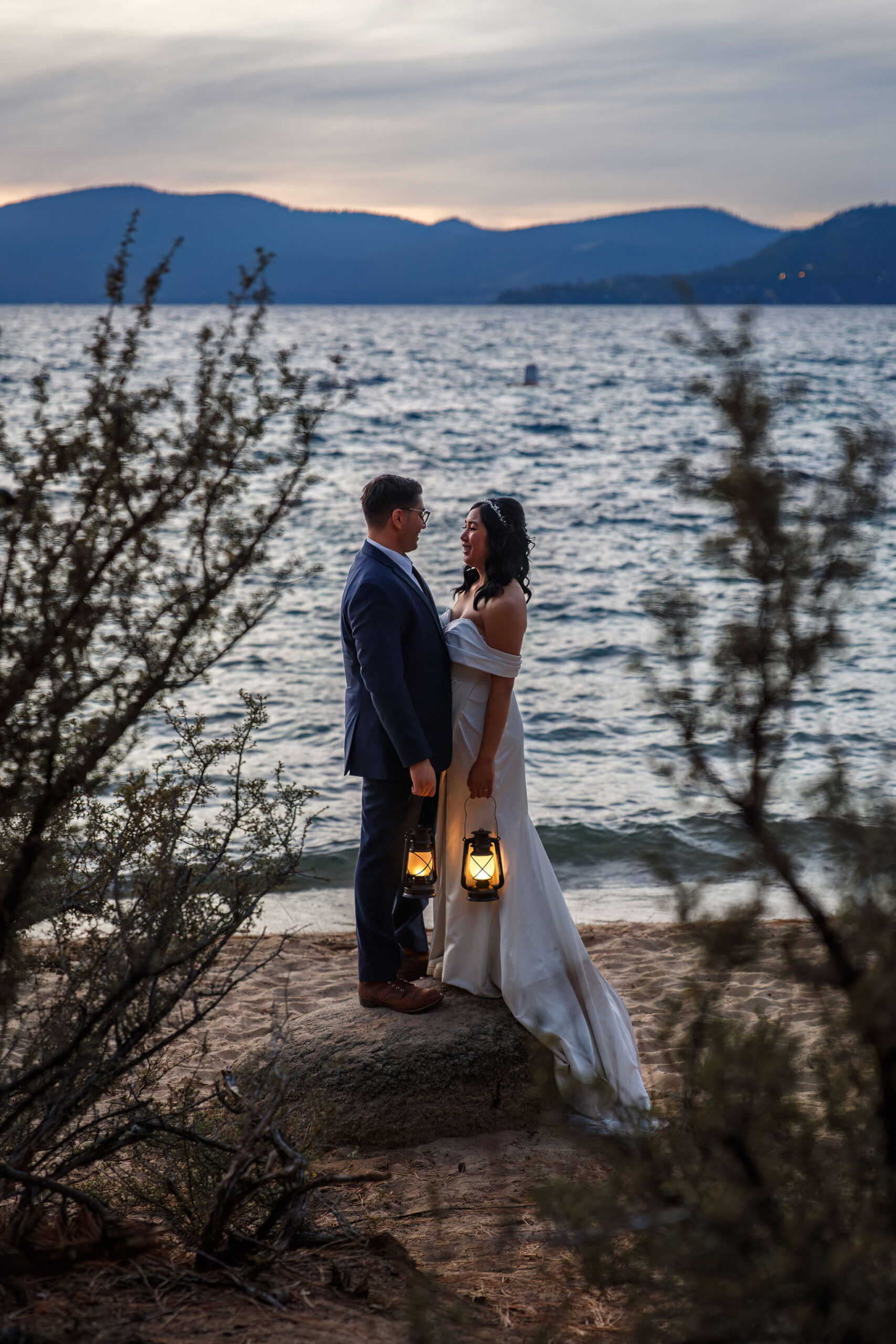 bride and groom holding lanterns as the sun starts to dip 