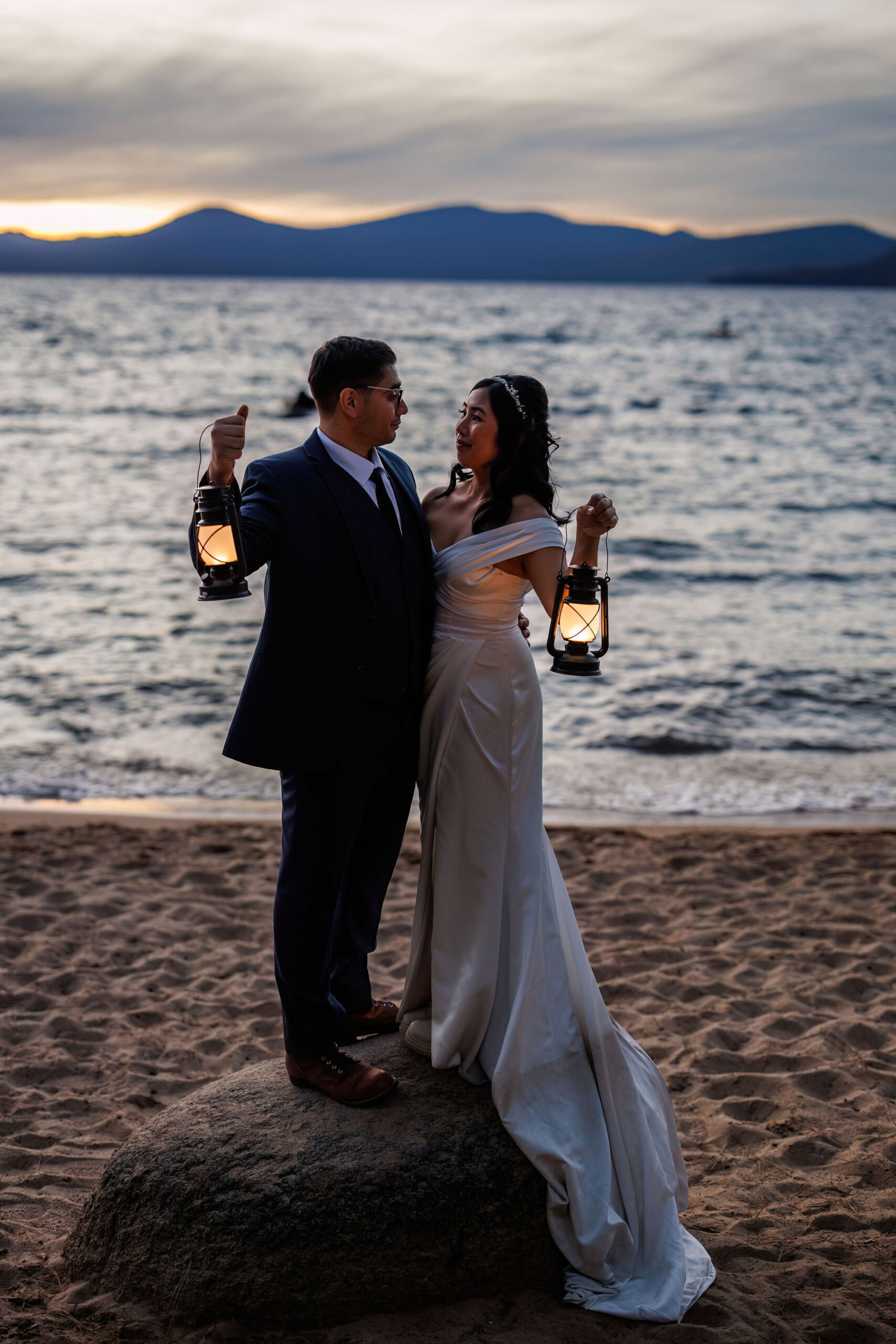 bride and groom portraits holding lanterns with lake tahoe behind them 