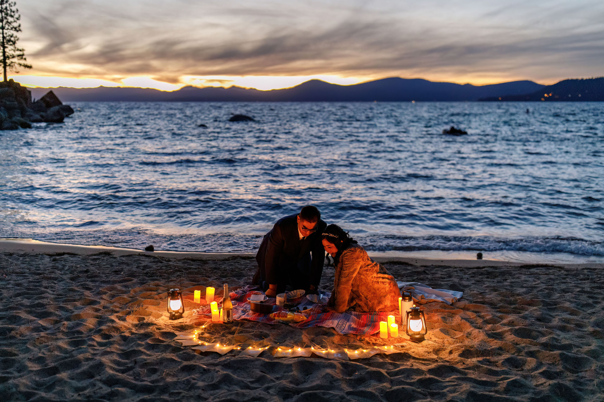 their beach picnic set up at night with the candles glowing 