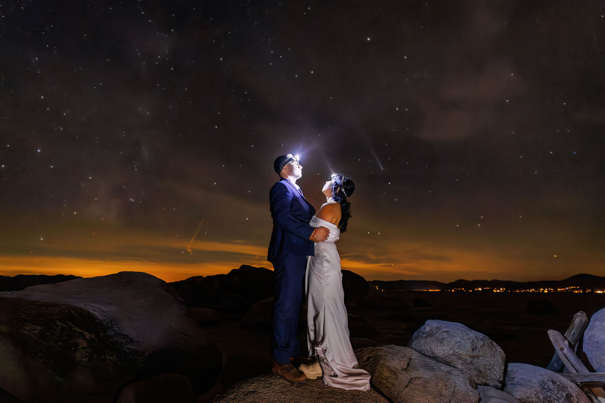 bride and groom with headlamps on looking up at the star filled sky 