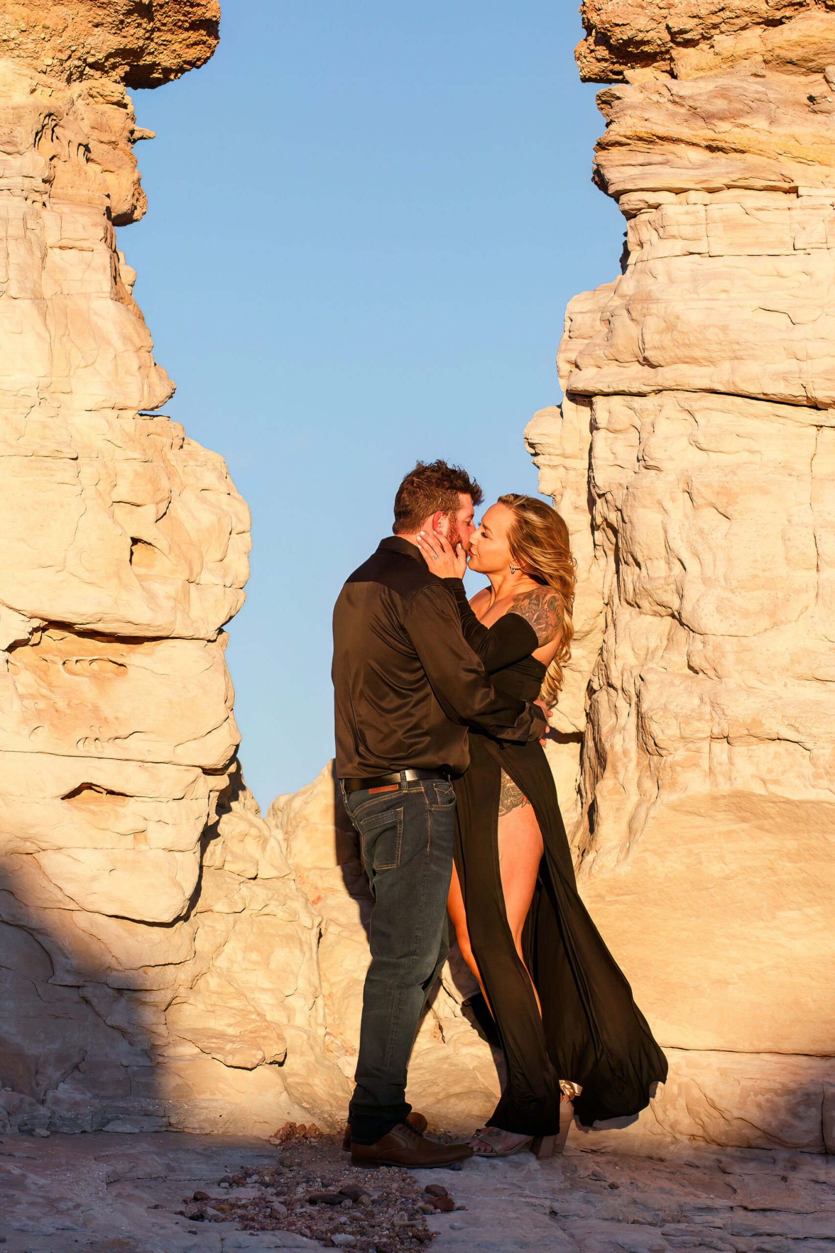 newly engaged couple kissing by a rock formation