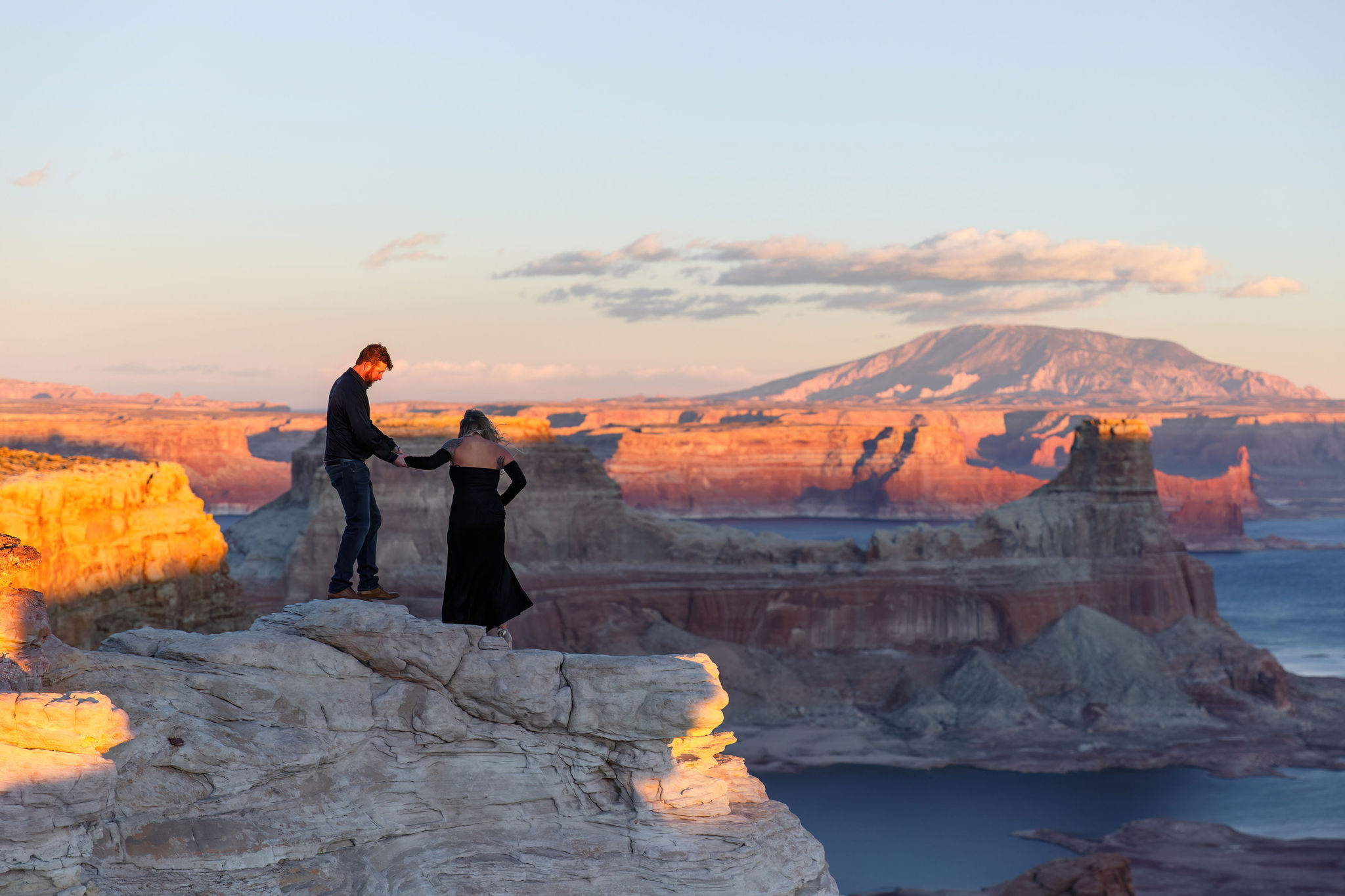 a man helping a woman down the rocks during their Utah engagement photos