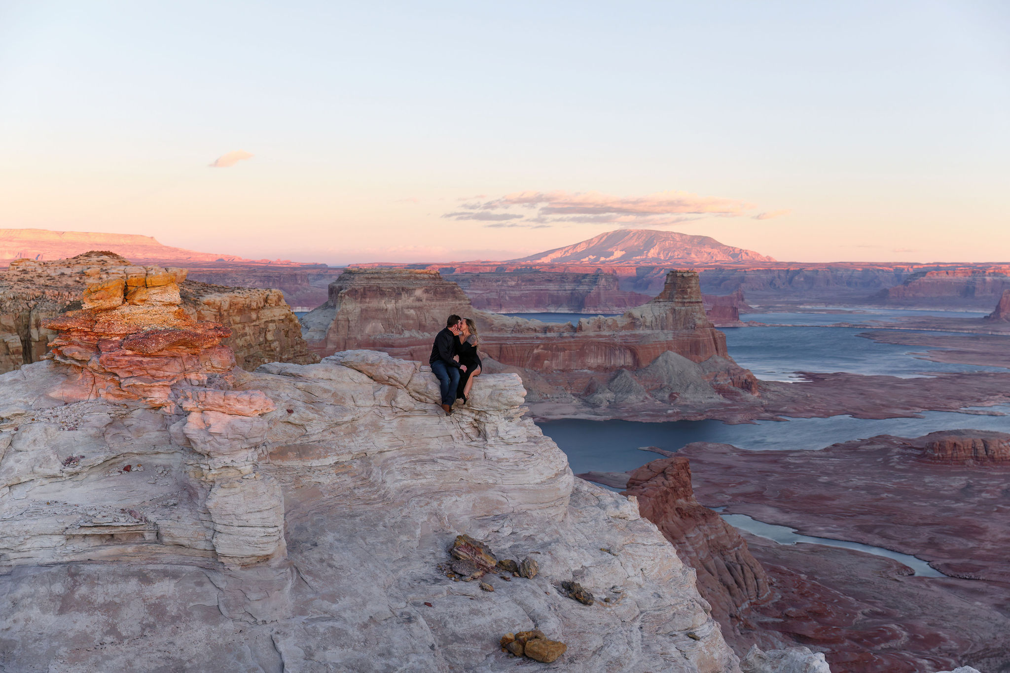 a couple sitting on the rock ledge at Altrom Point during sunset 