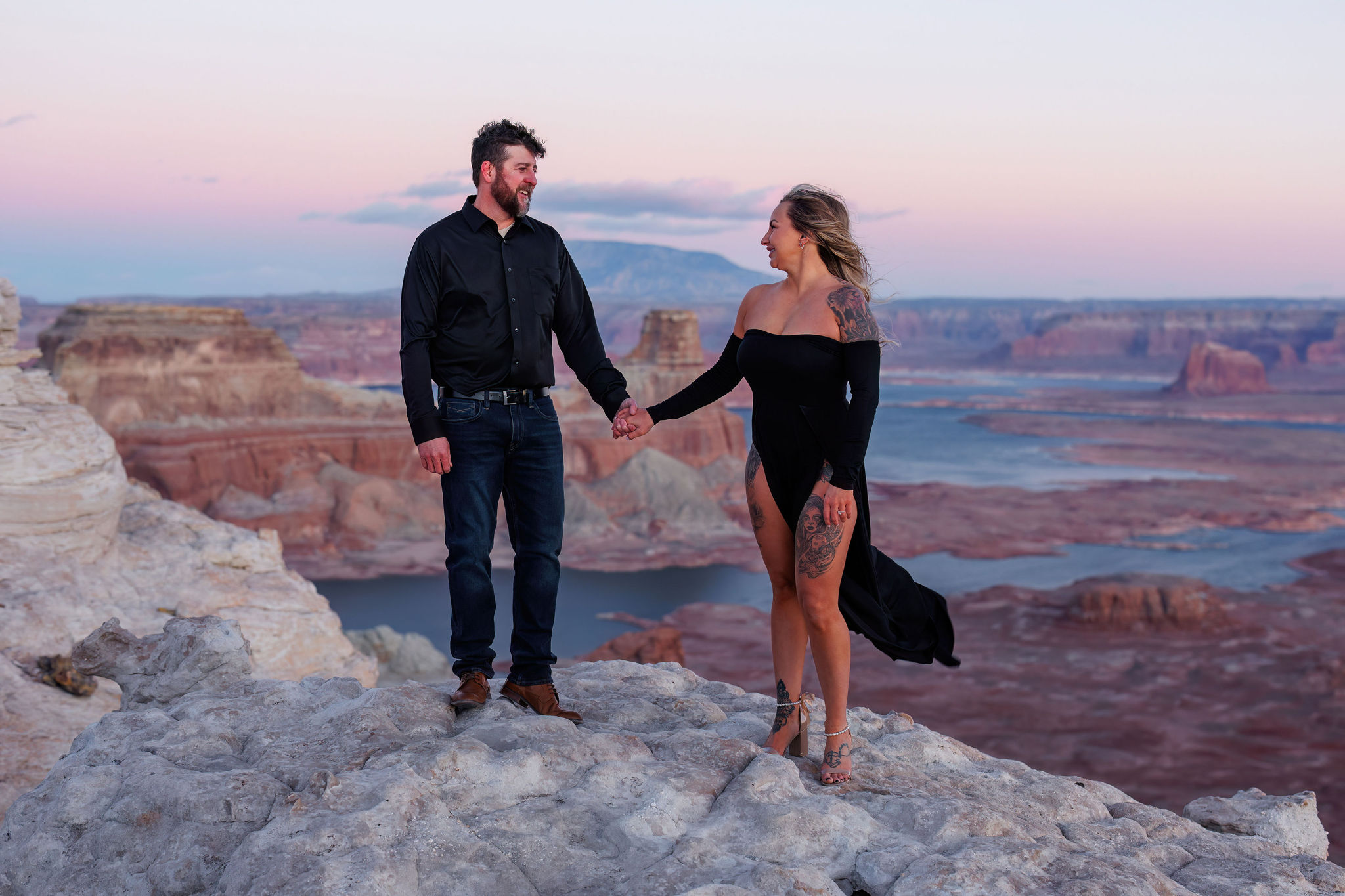 a couple holding hands standing on a view point at Lake Powell 