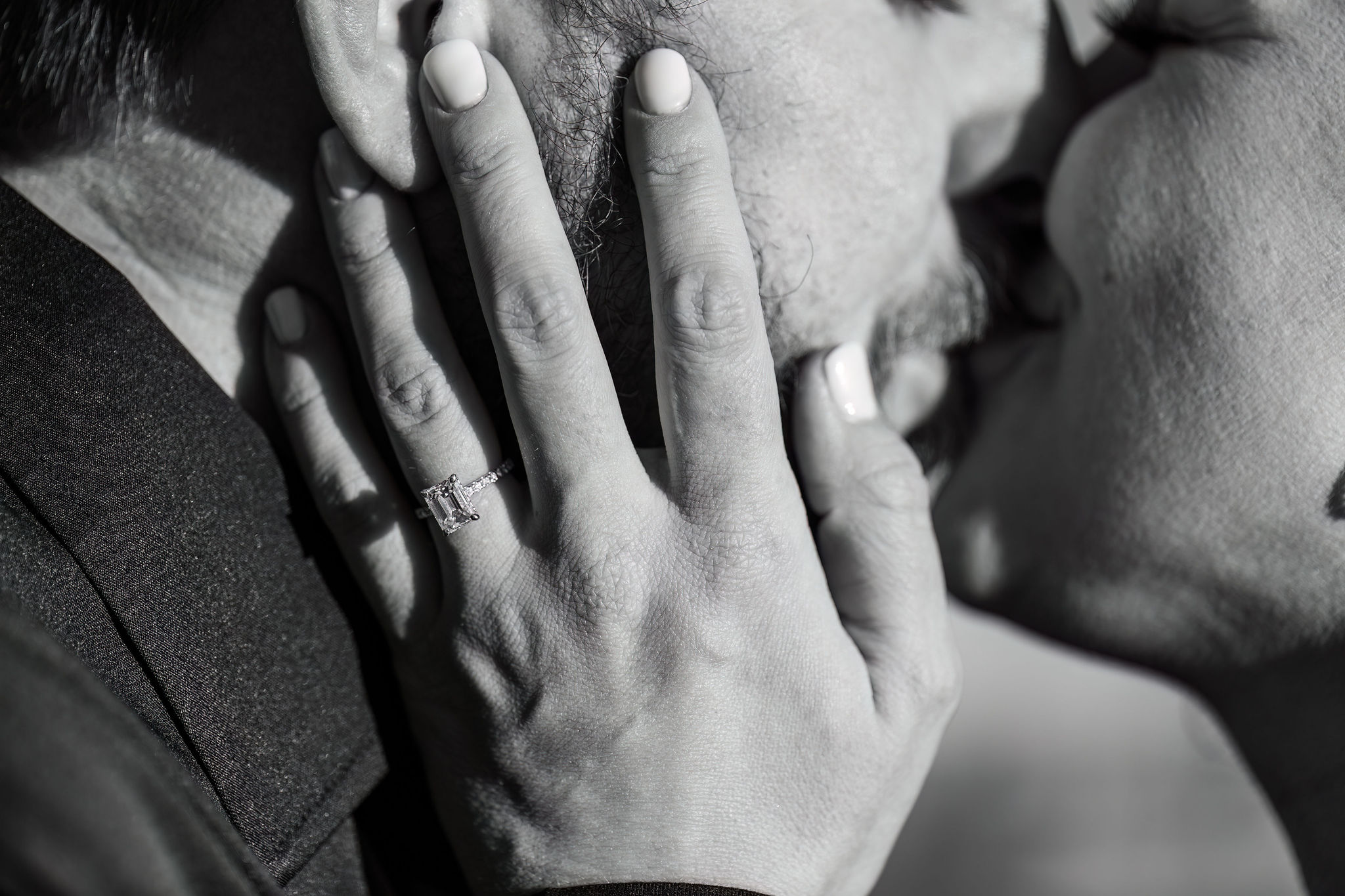 a close up of a woman's engagement ring as she kisses her fiance 