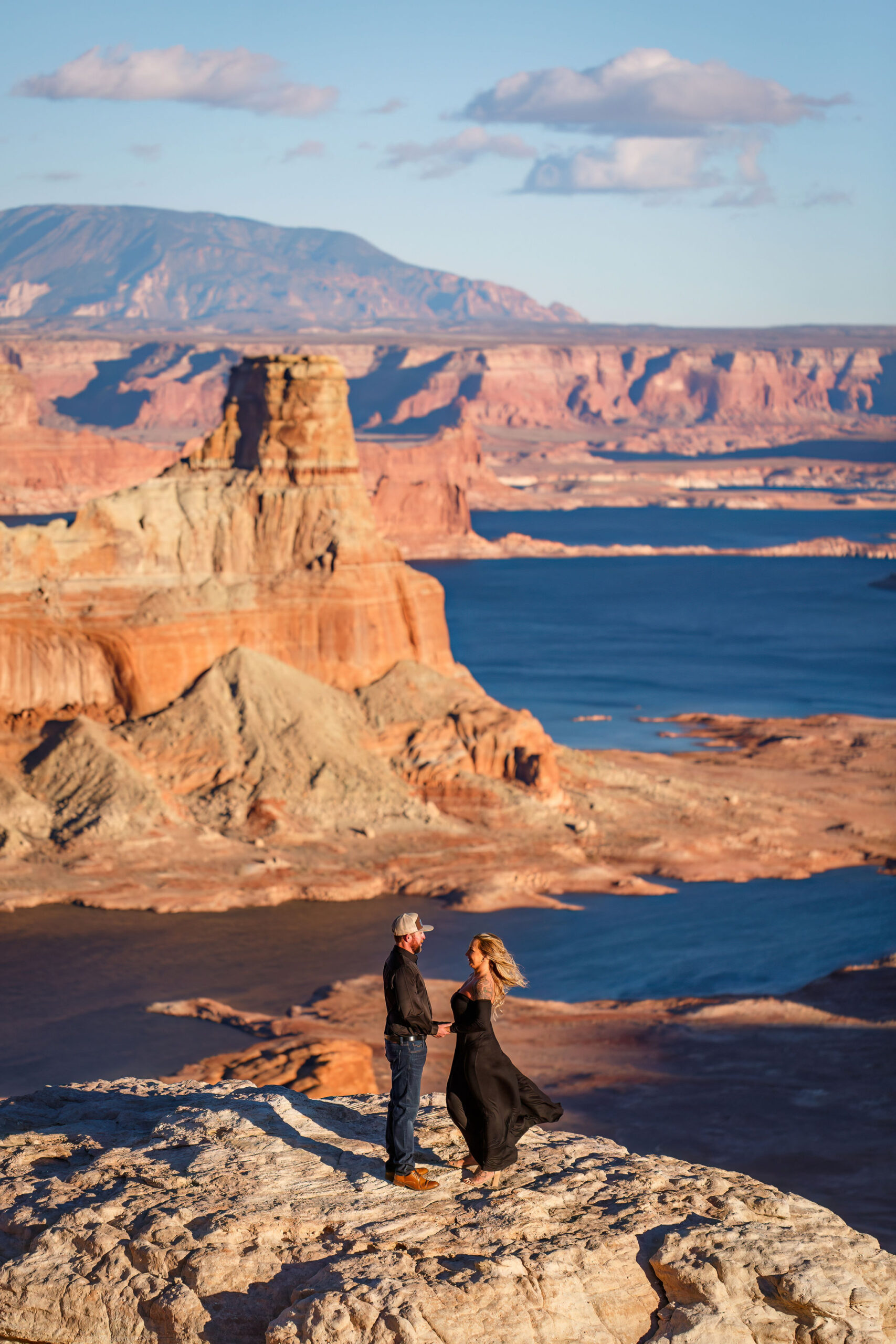 newly engaged couple holding hands with Lake Powell below them during their Utah engagement photos