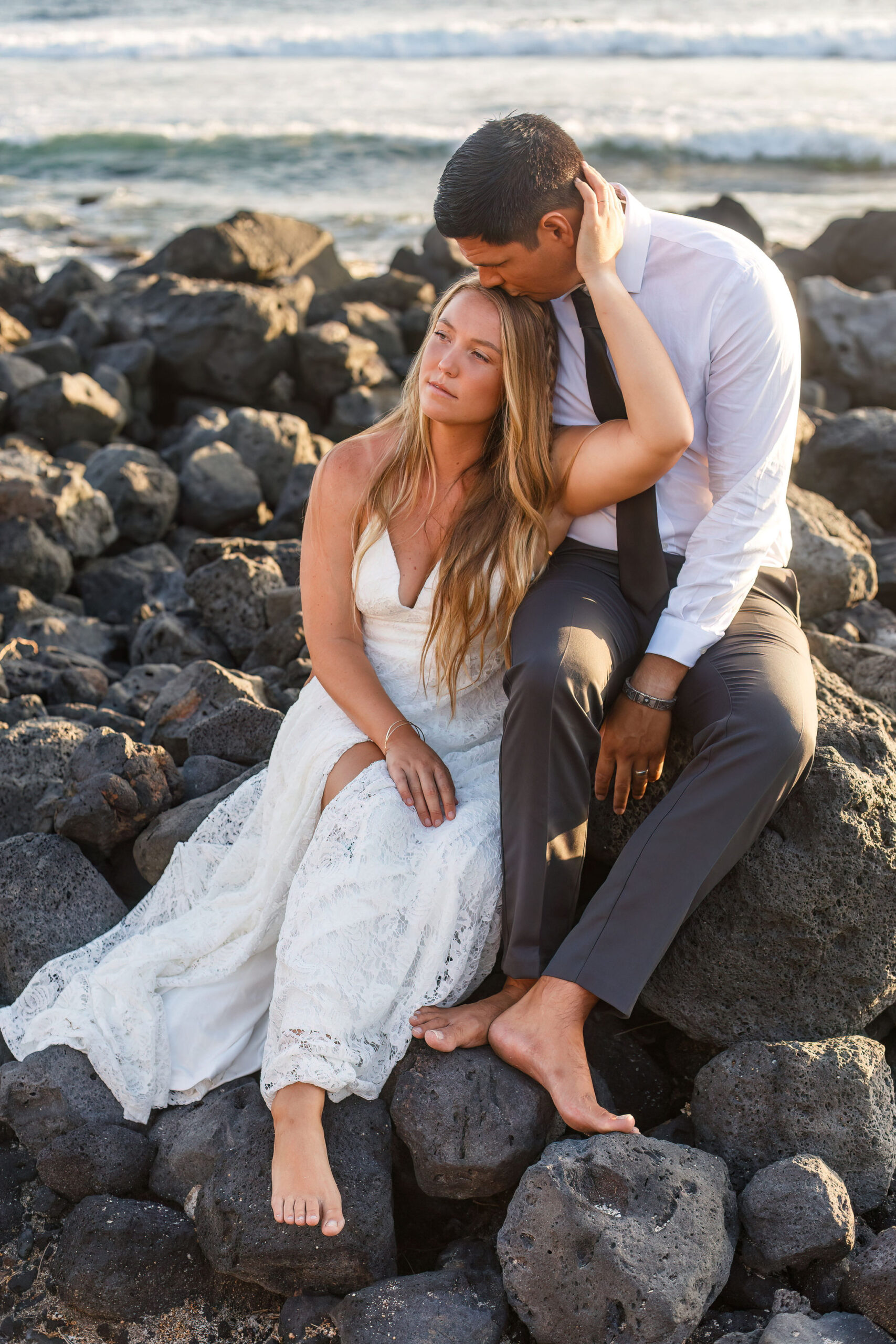 a couple sitting on rocks at the beach for their Hawaii elopement 