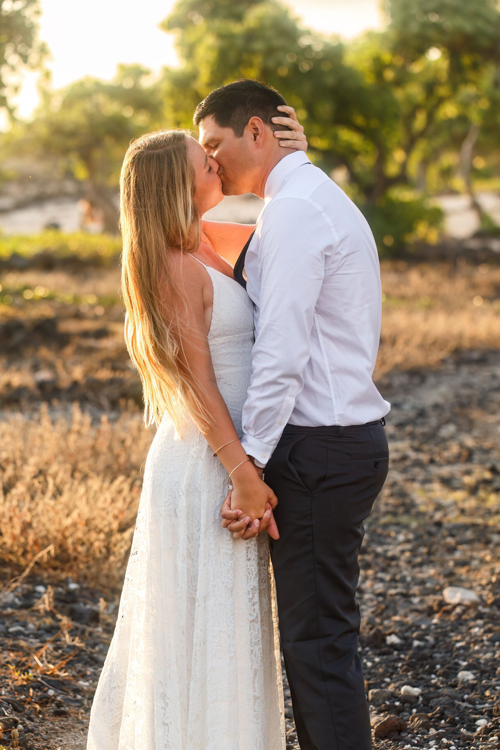 newly weds kissing on the beach as the sun sets 