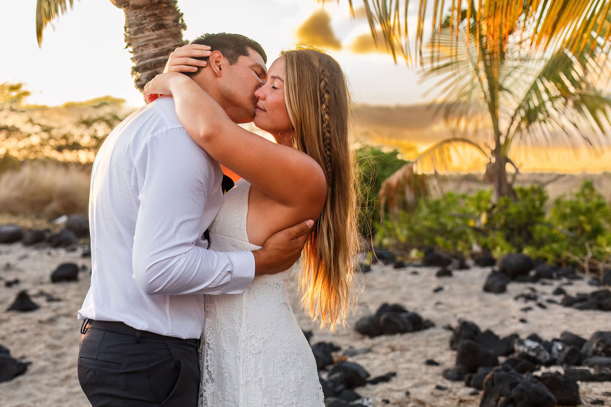 a man kissing a woman's cheek on the beach in Hawaii 