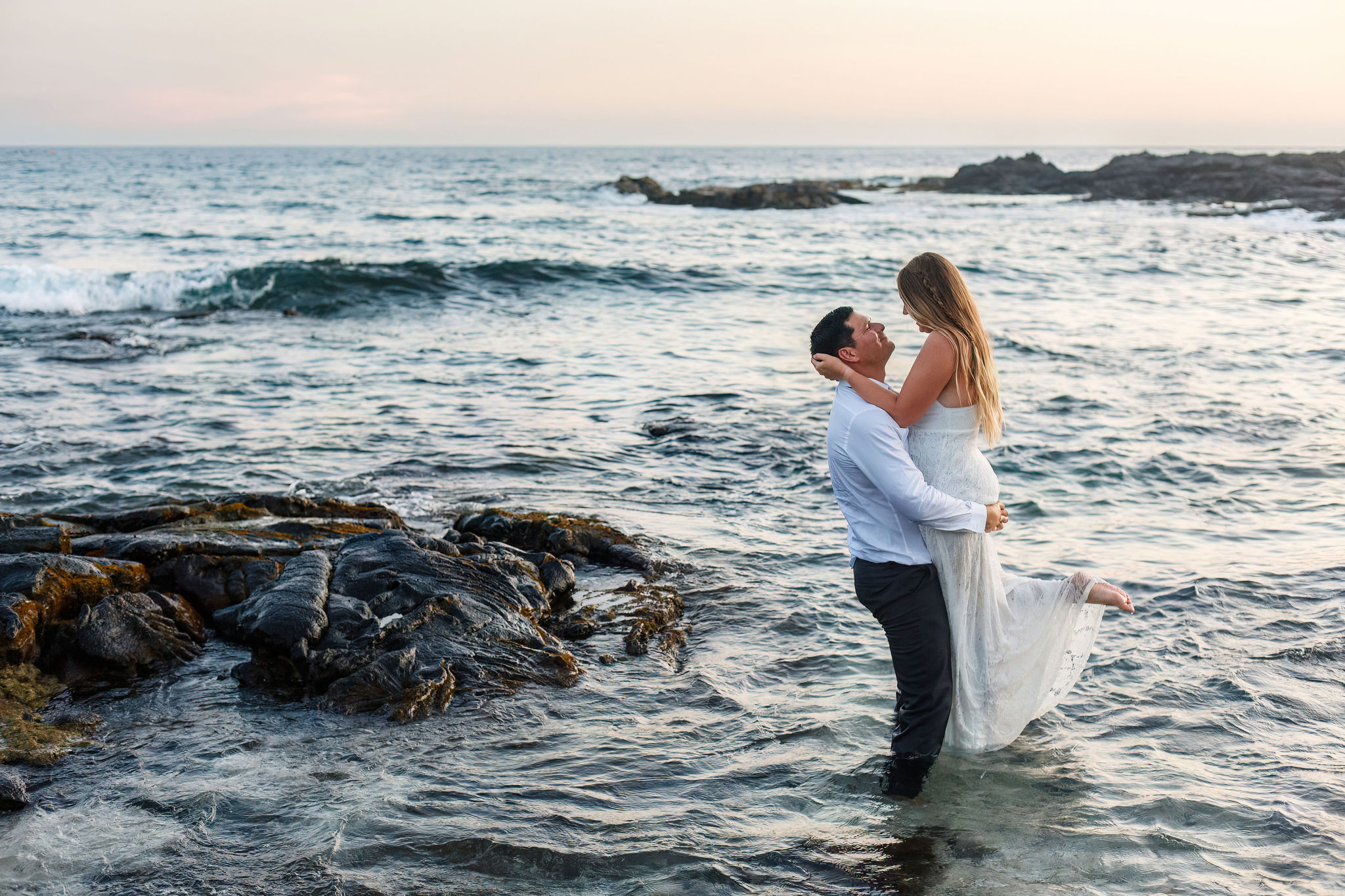 a man holding up a woman in the ocean during their Hawaii elopement 