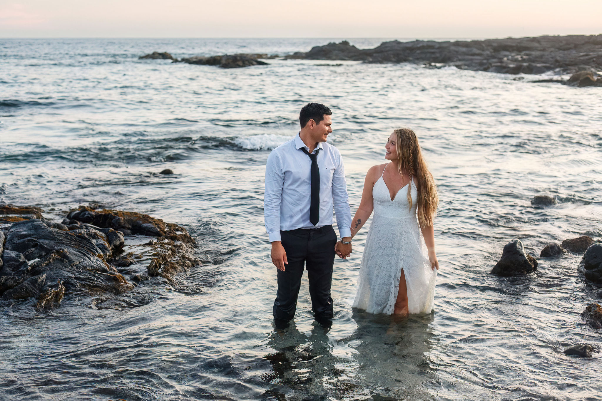 a couple standing in the ocean and smiling at each other 