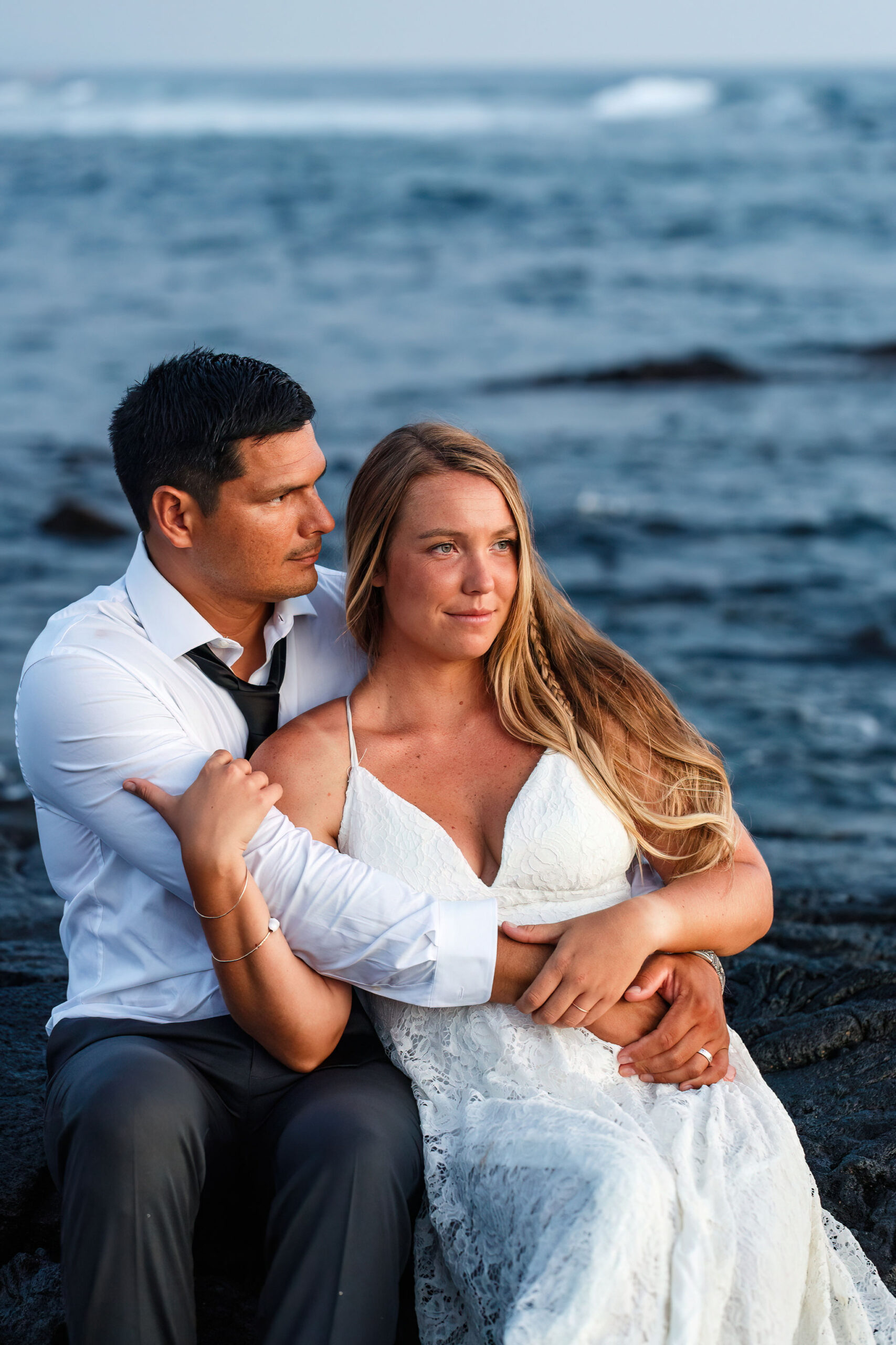 a couple sitting together and looking off into the distance at their Hawaii elopement 