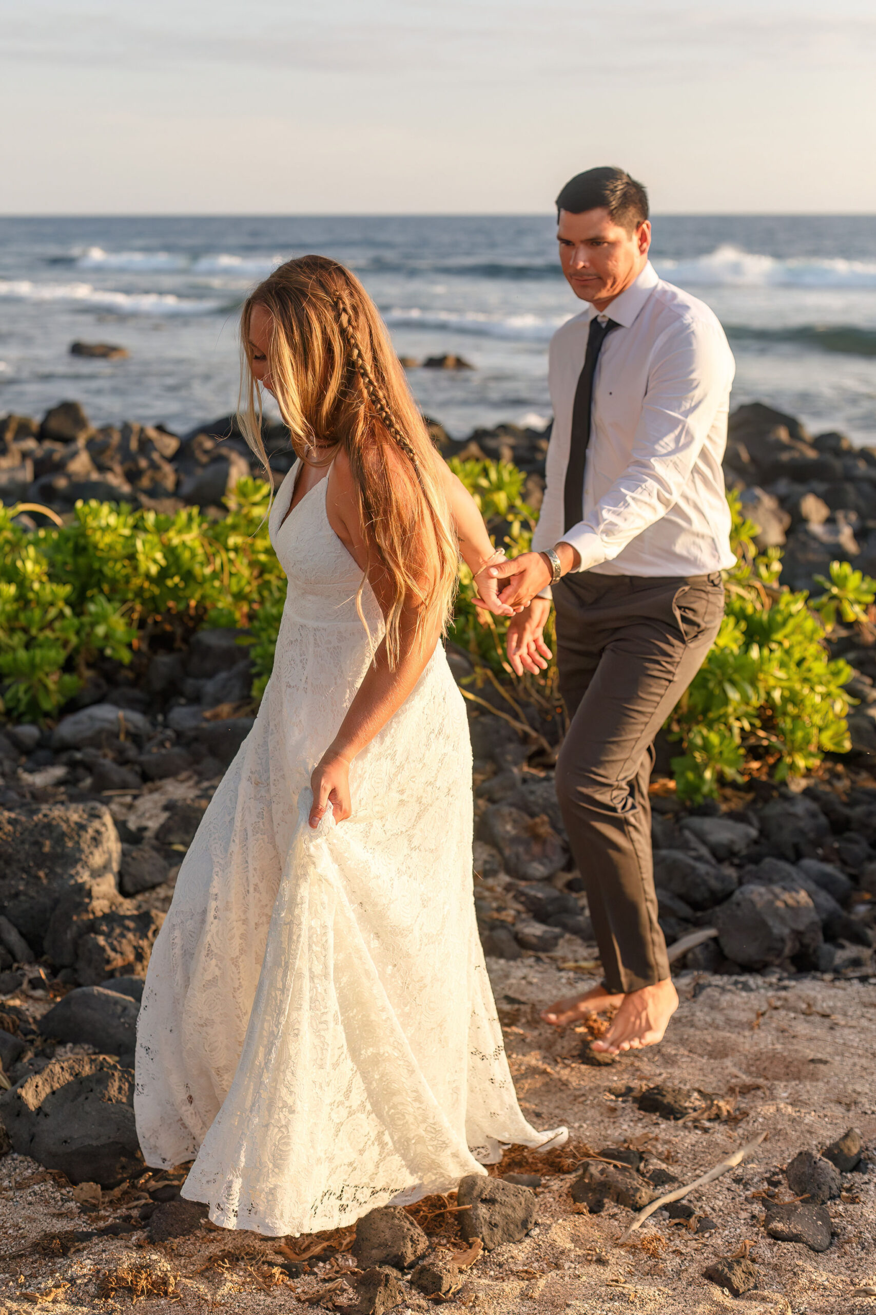 a couple walking barefoot and hand in hand down the beach 