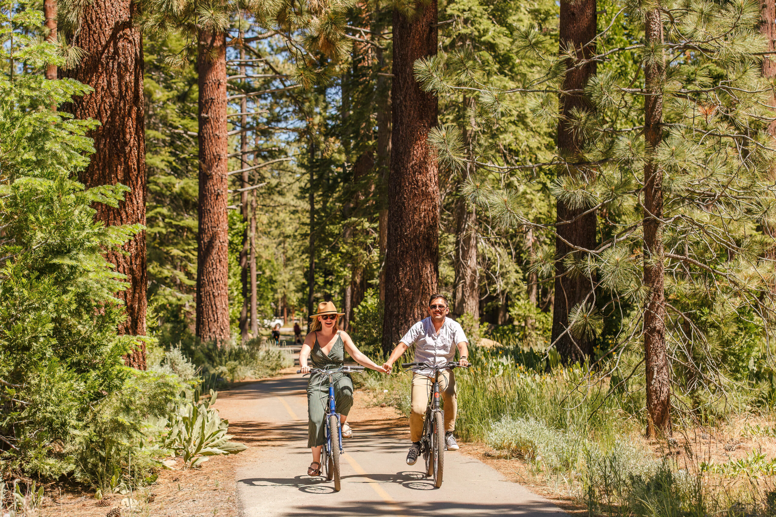 newly engaged couple holding hands as they ride the bike trails for Lake Tahoe engagement photos