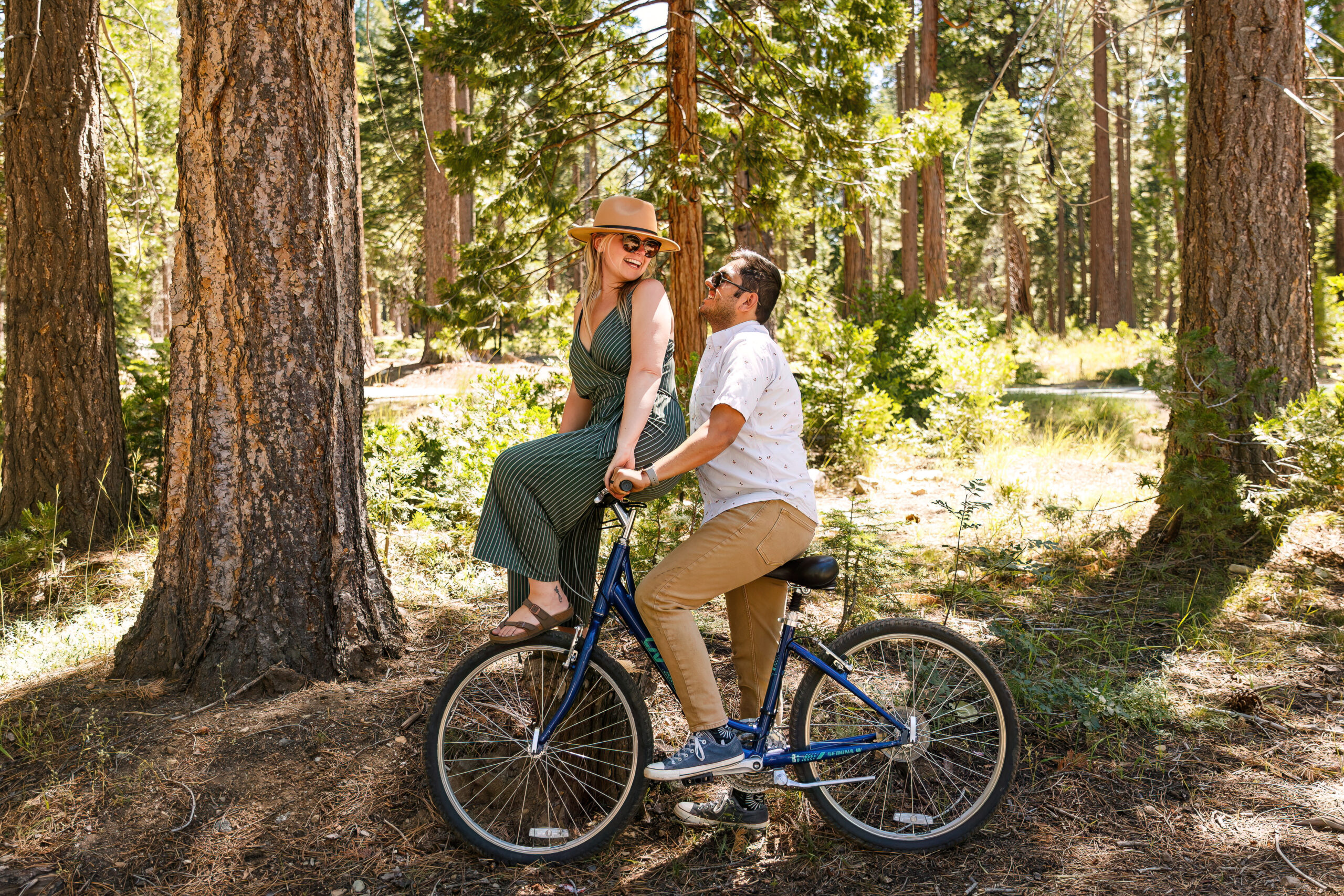 newly engaged couple riding a bike together as the woman sits on the handlebars