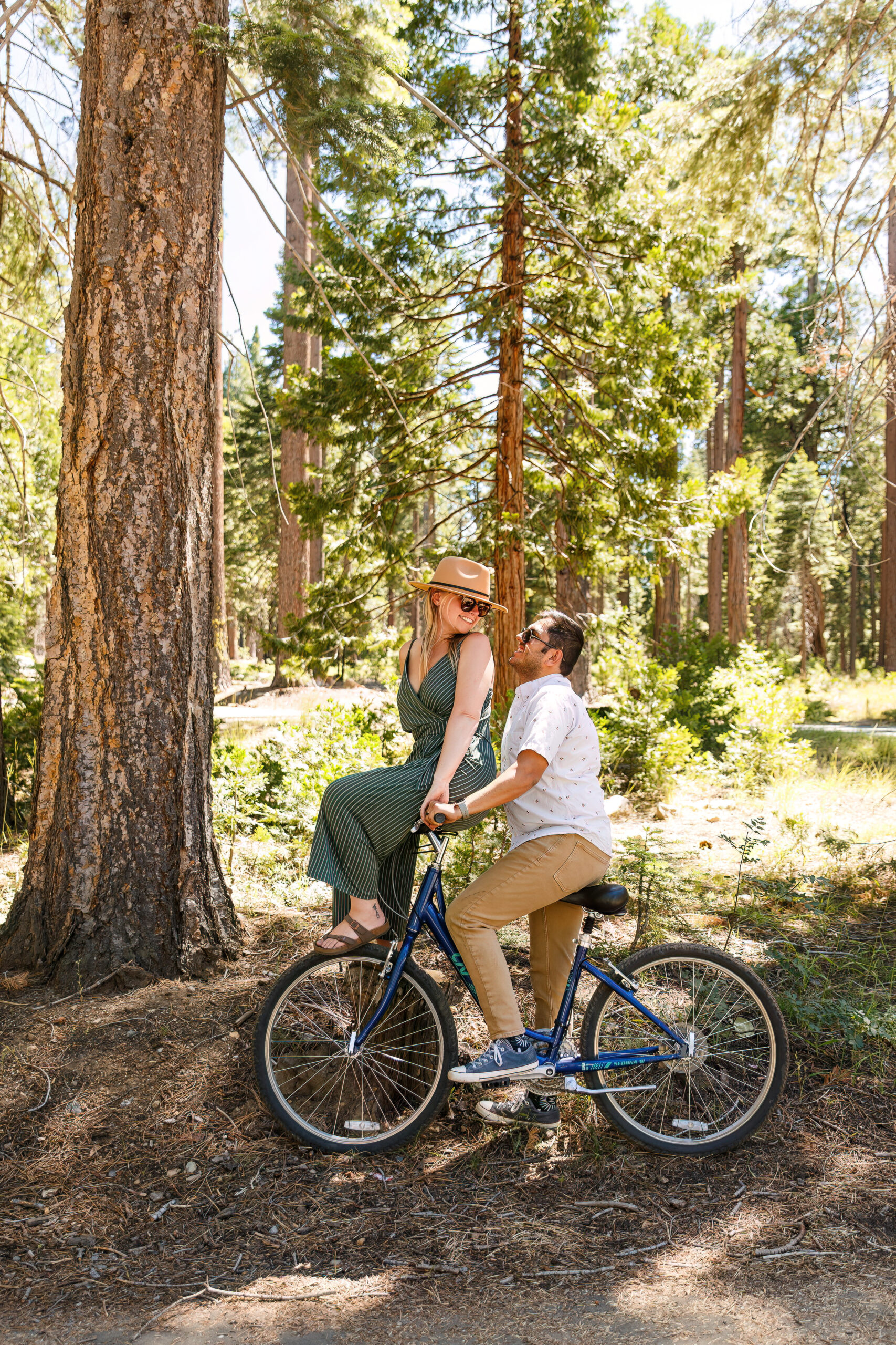 newly engaged couple smiling at each other as they do bike tricks