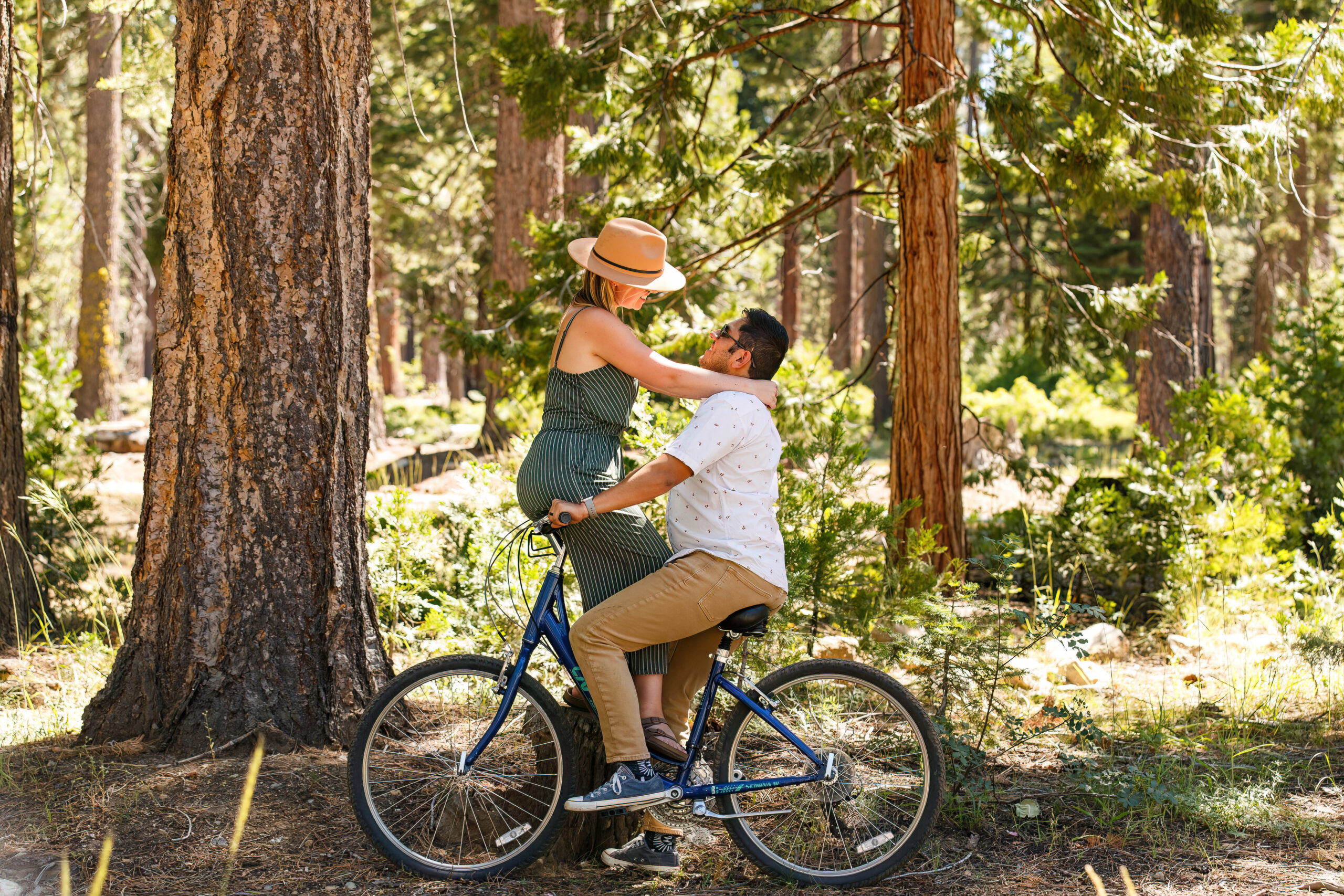 a couple riding a bike together as the woman sits on the handlebars